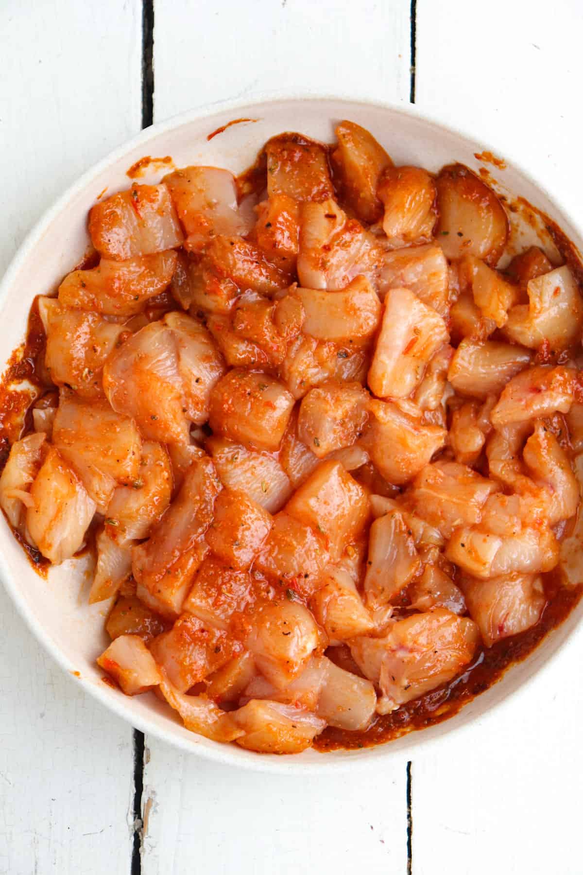raw chicken pieces marinating in a shallow bowl.