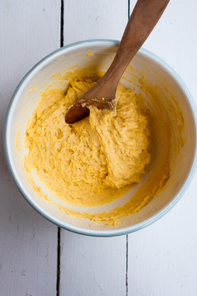 cornbread batter mixed with a wooden spoon.