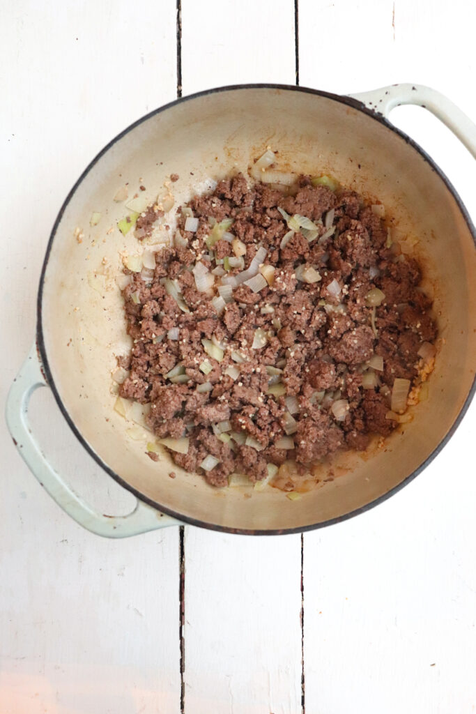 browned ground beef with seasonings in a dutch oven.