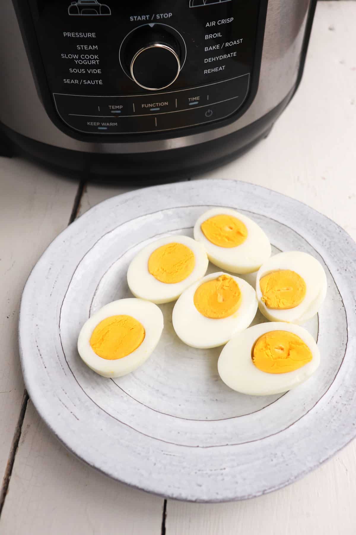 plated of hard boiled egg halves in front of ninja foodi.