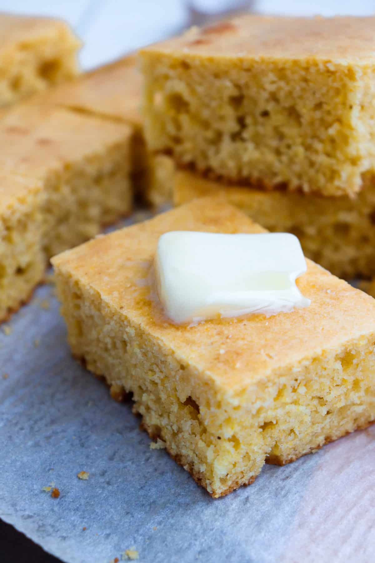 sour cream cornbread piece with pat of butter on top. 