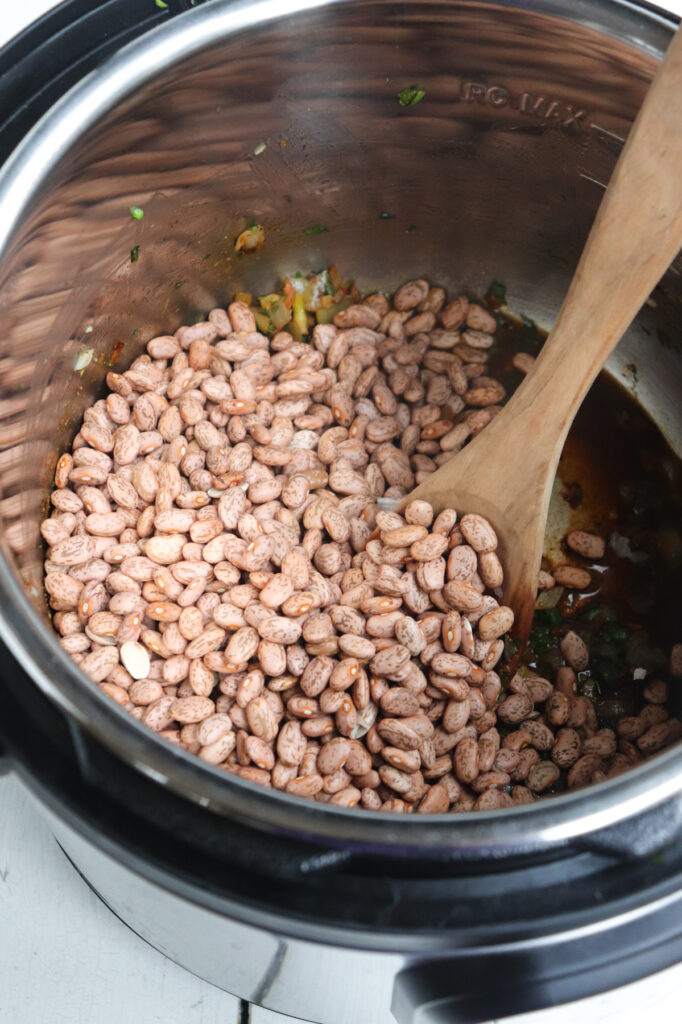 dry beans being stirred in with a wooden spoon.