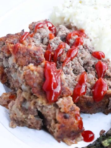 two slices venison meatloaf with ketchup drizzled on top.