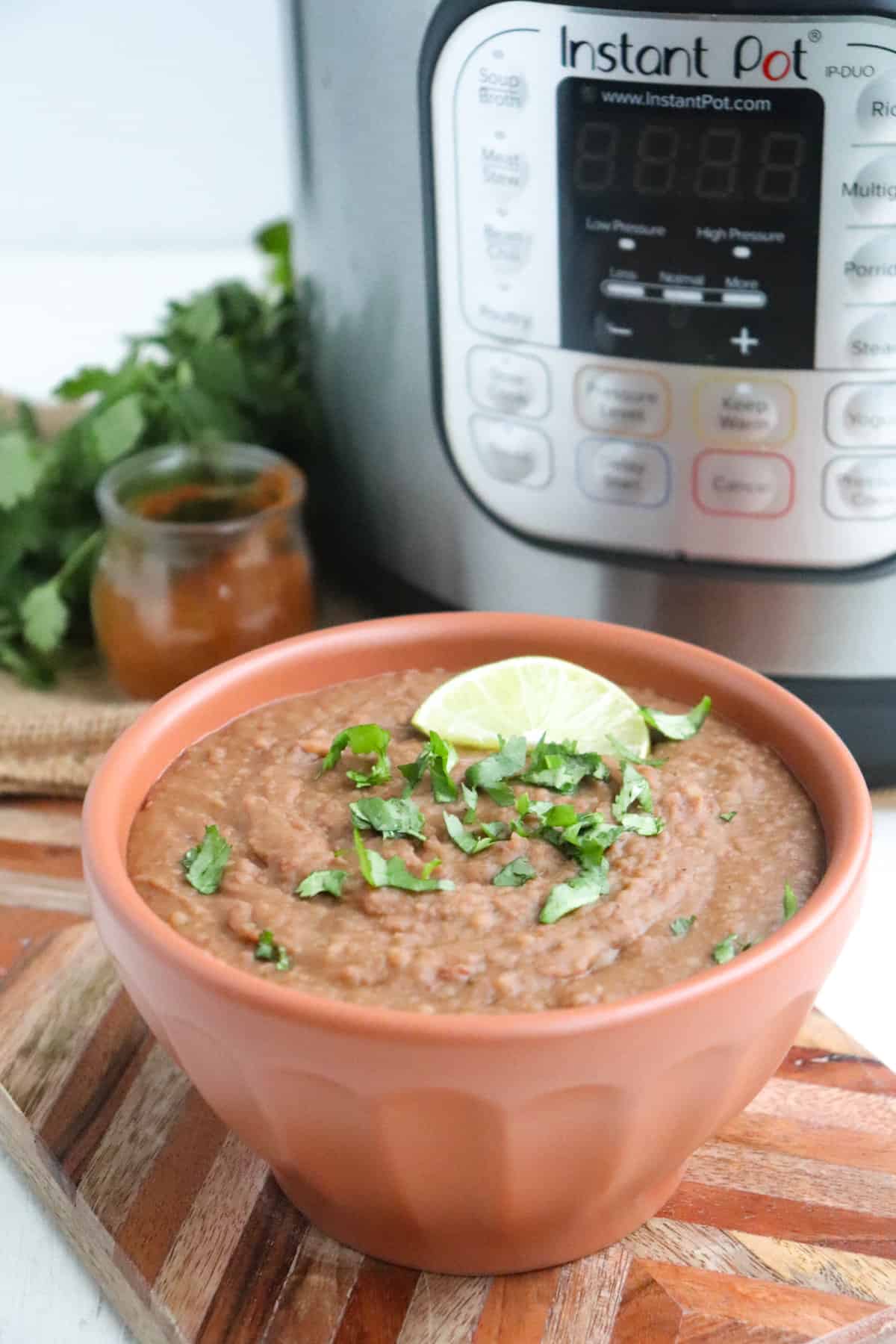 bowl of finished refried beans in front of Instant Pot. 