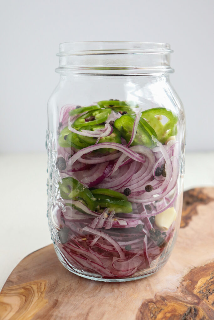 side view of large mason jar sliced with onions and other spices.