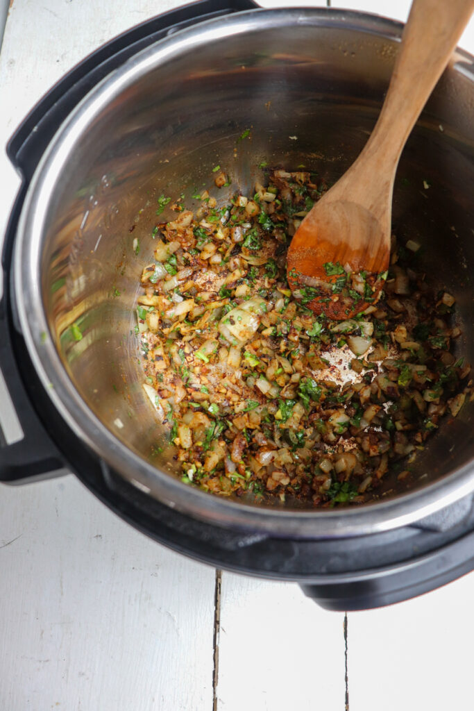sauteed seasonings stirred with wooden spoon.