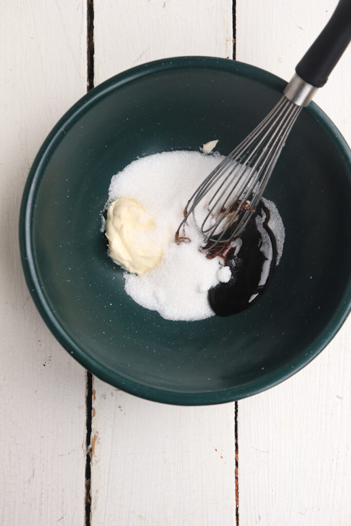 vanilla, cream cheese, and sugar unmixed in a small green bowl.