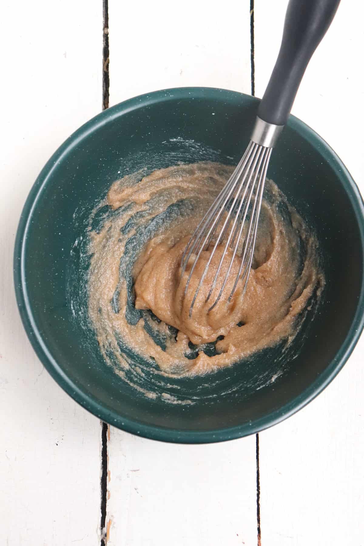 vanilla, cream cheese, and sugar whisked in a small green bowl.