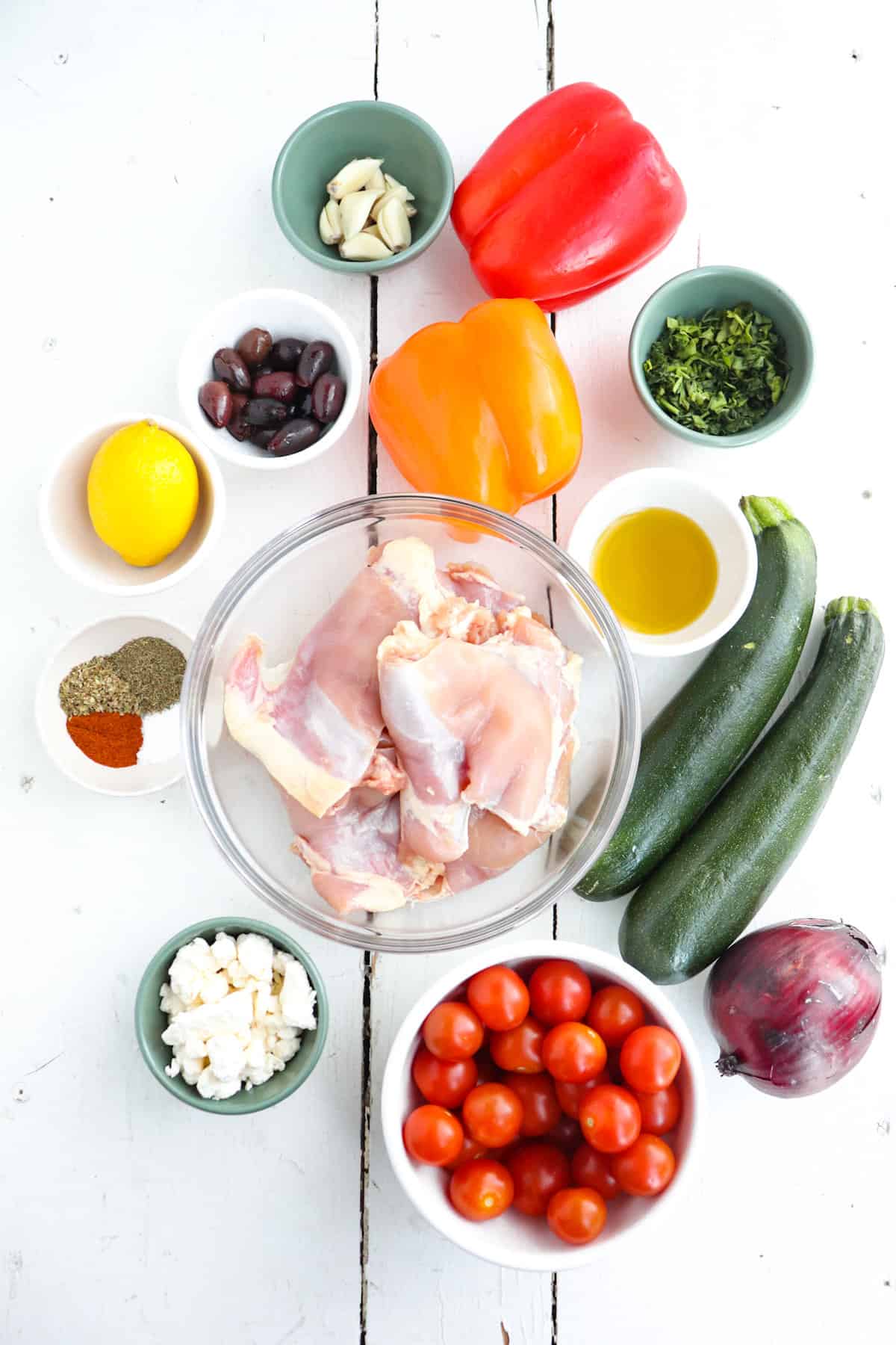 ingredients for greek chicken tray bake on a white background.