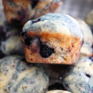 up close of one mini blueberry muffin on top of several muffins.