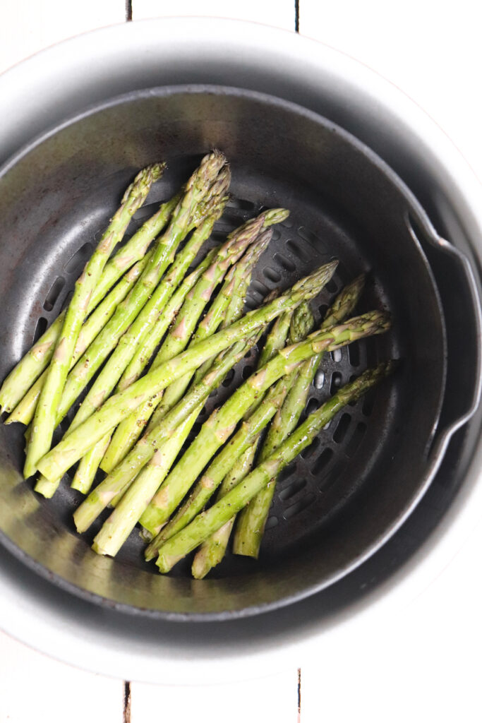 raw asparagus in ninja foodi air fryer basket.