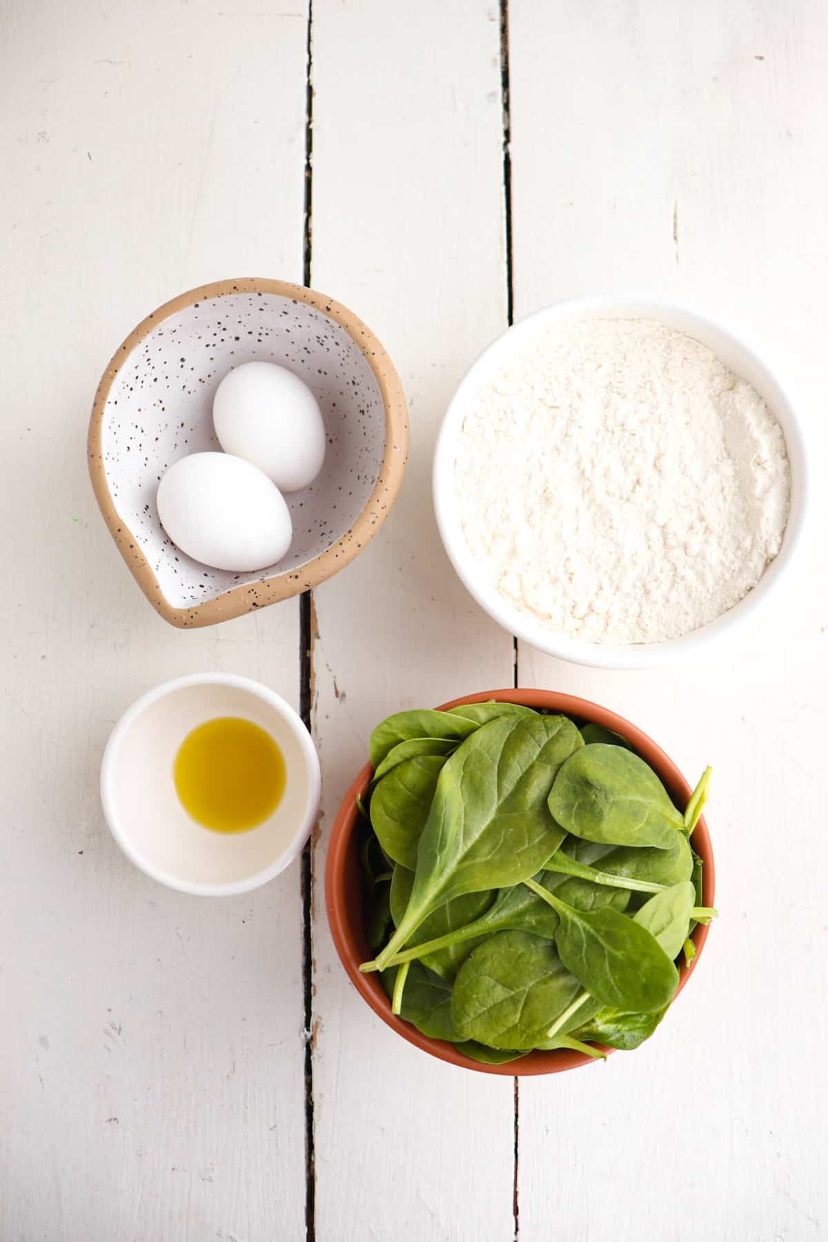 homemade spinach pasta dough ingredients on a white background.