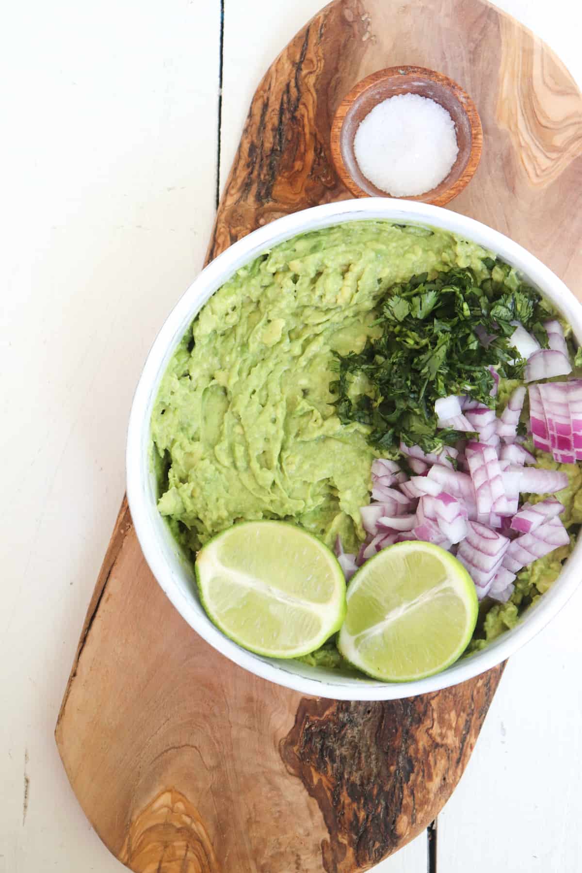 4 ingredient guacamole in a white bowl unmixed with salt in the background.