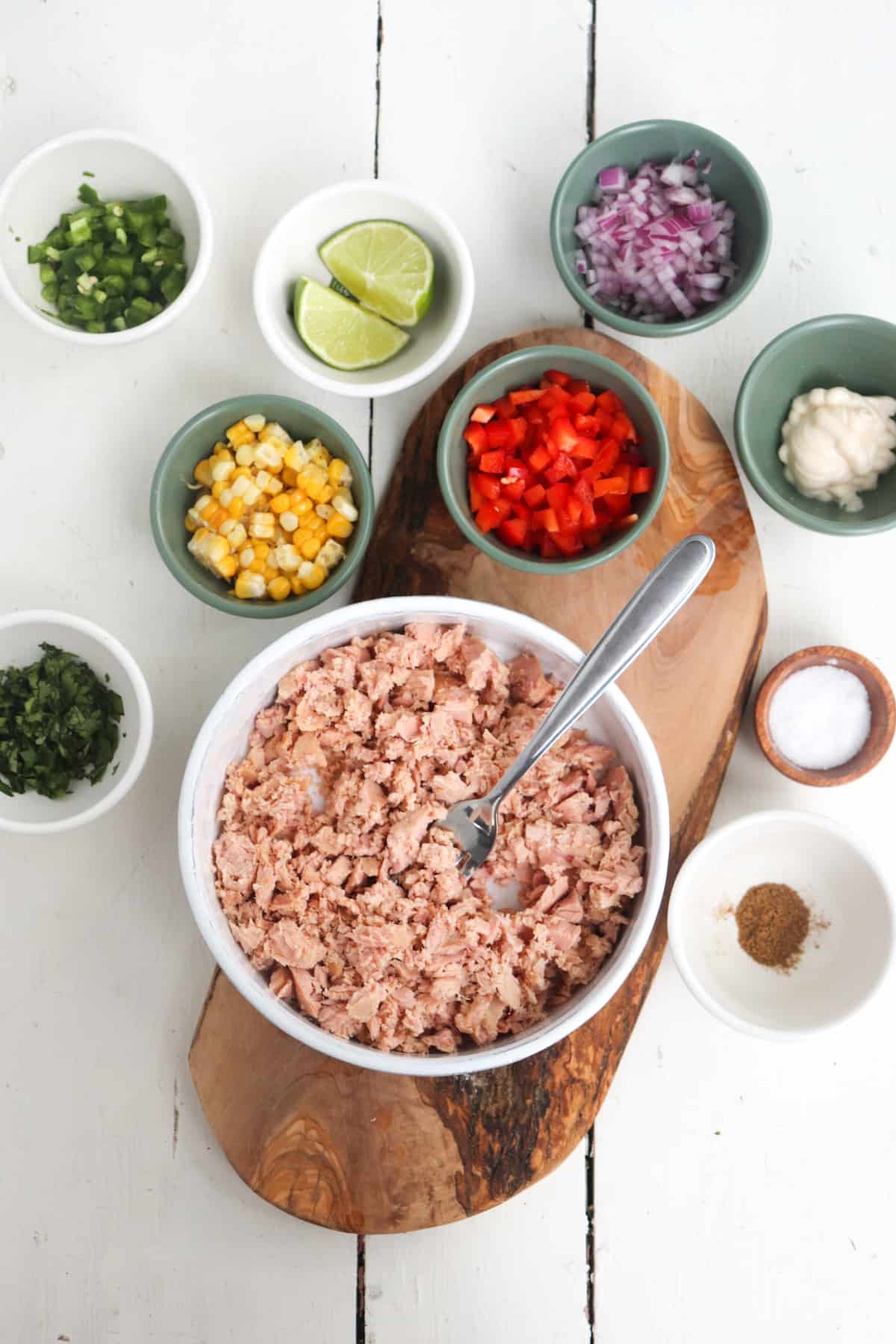 mashed tuna in a bowl in the middle of other salad ingredients.