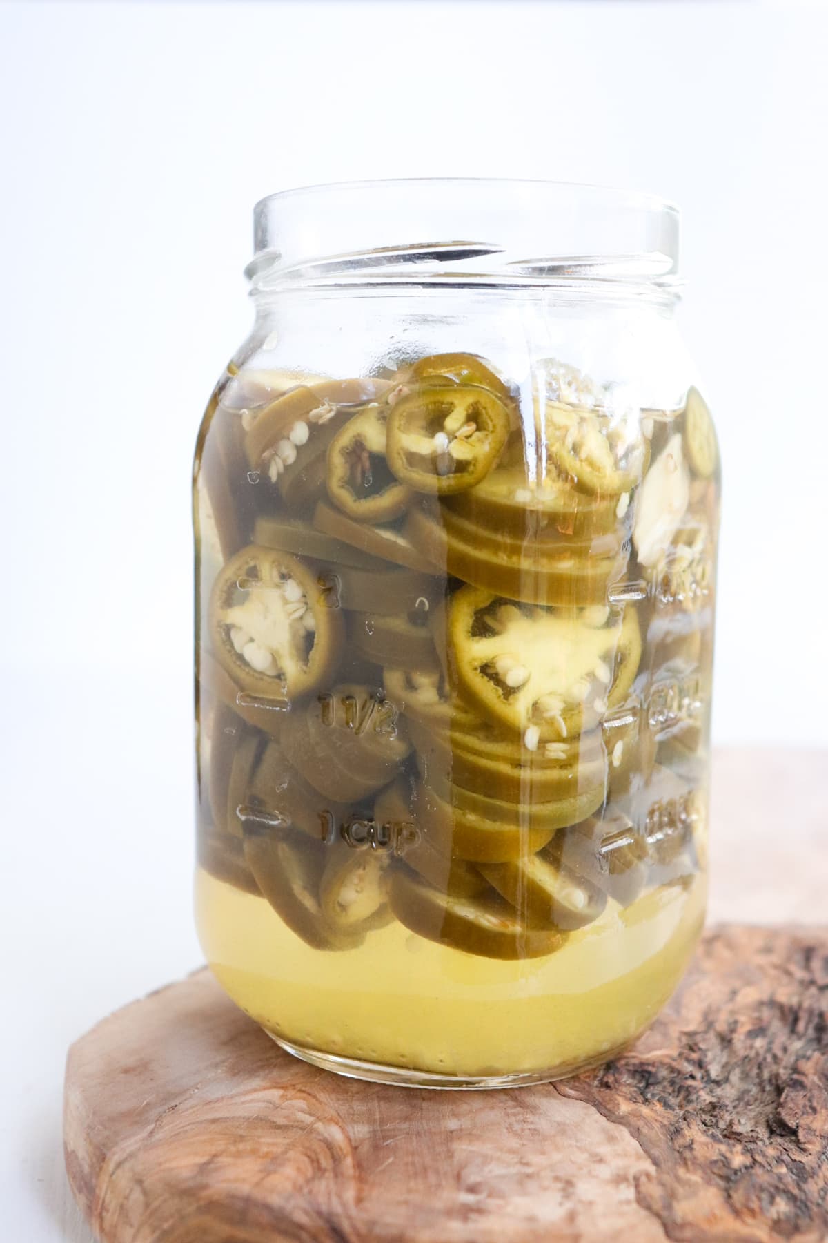 side view of glass jar filled with jalapenos and brining liquid at the end of the process.