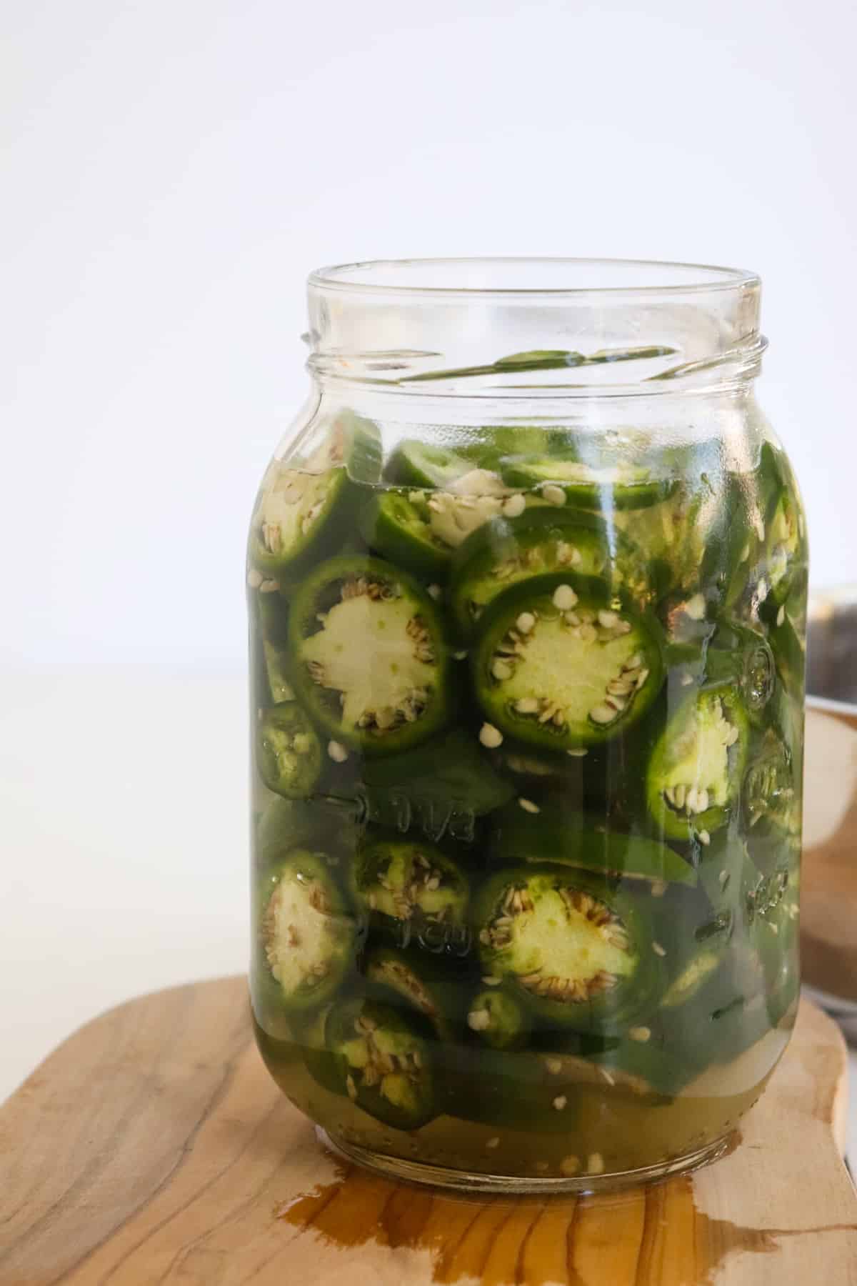 side view of glass jar filled with jalapenos and brining liquid at the beginning of the process.