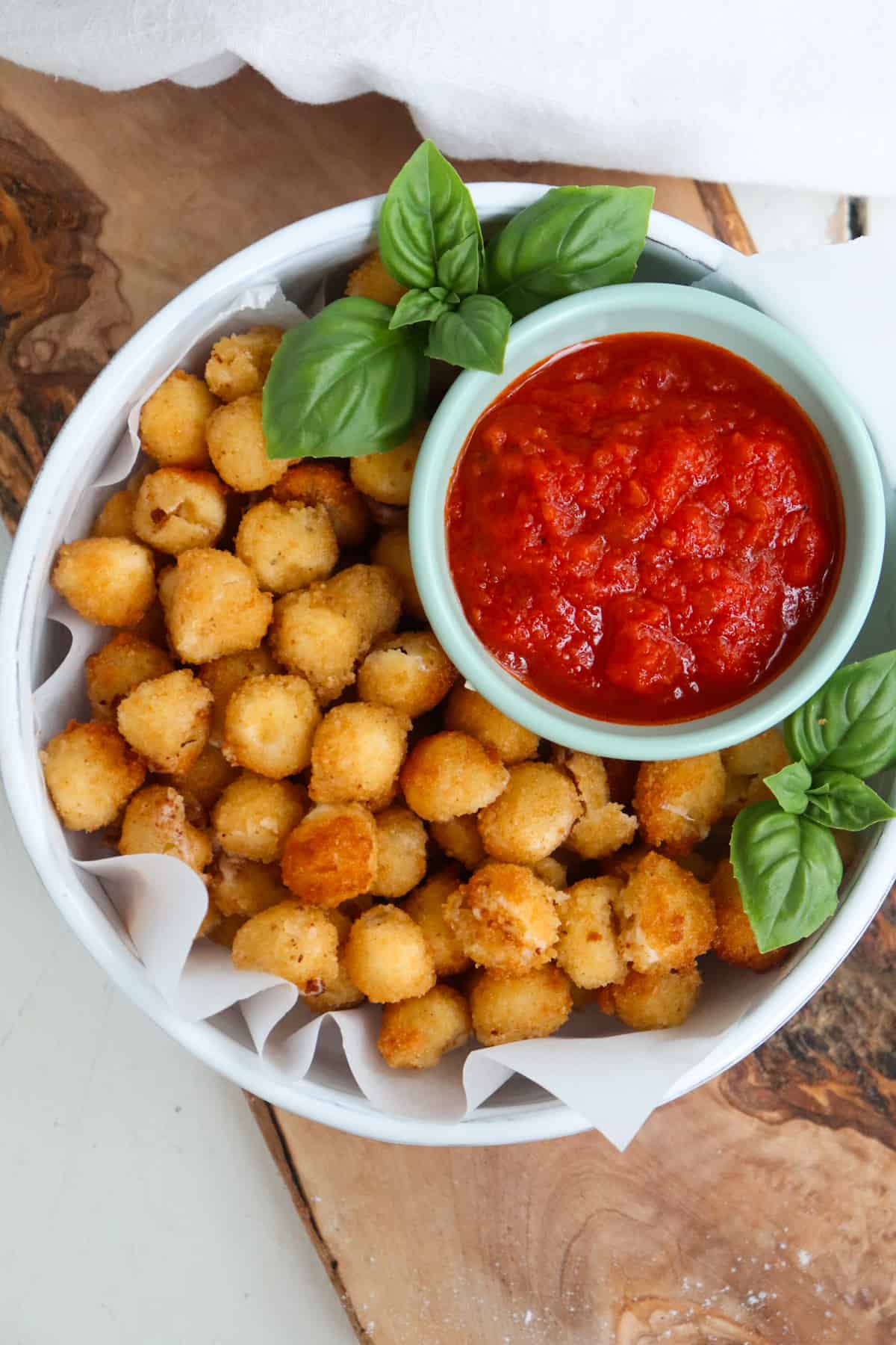 a plate of mozzarella balls that is served with marinara sauce and a basil garnish.