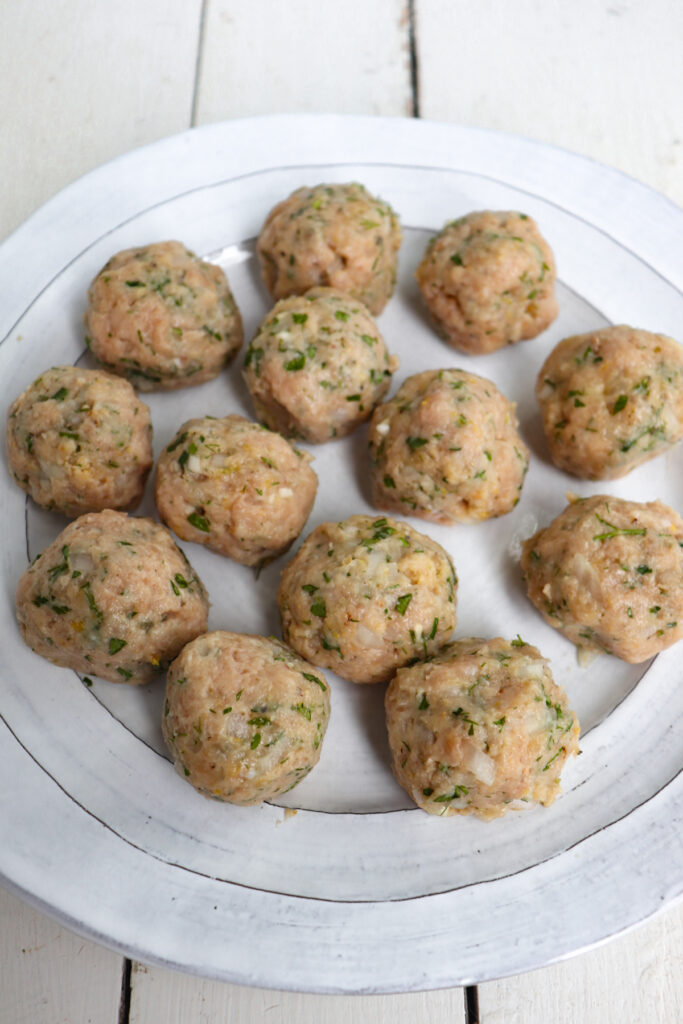 formed greek meatballs on a white plate.