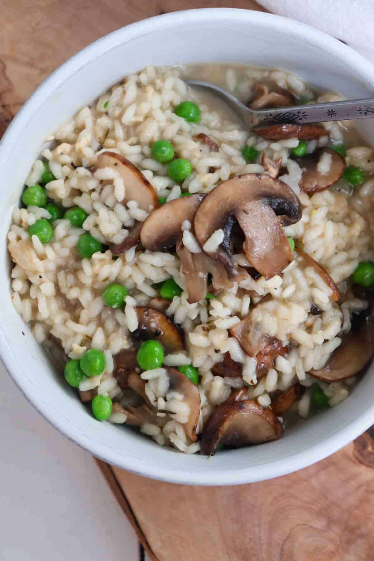 up close of mushroom pea risotto in a white bowl.