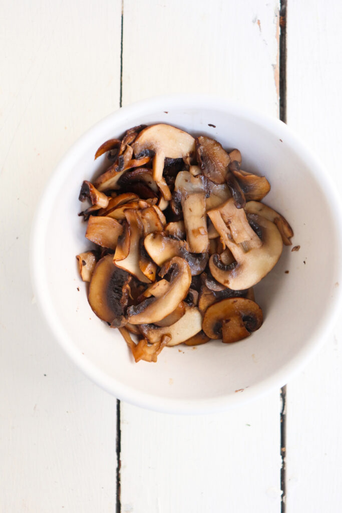 sauteed cremini mushrooms in a white bowl.