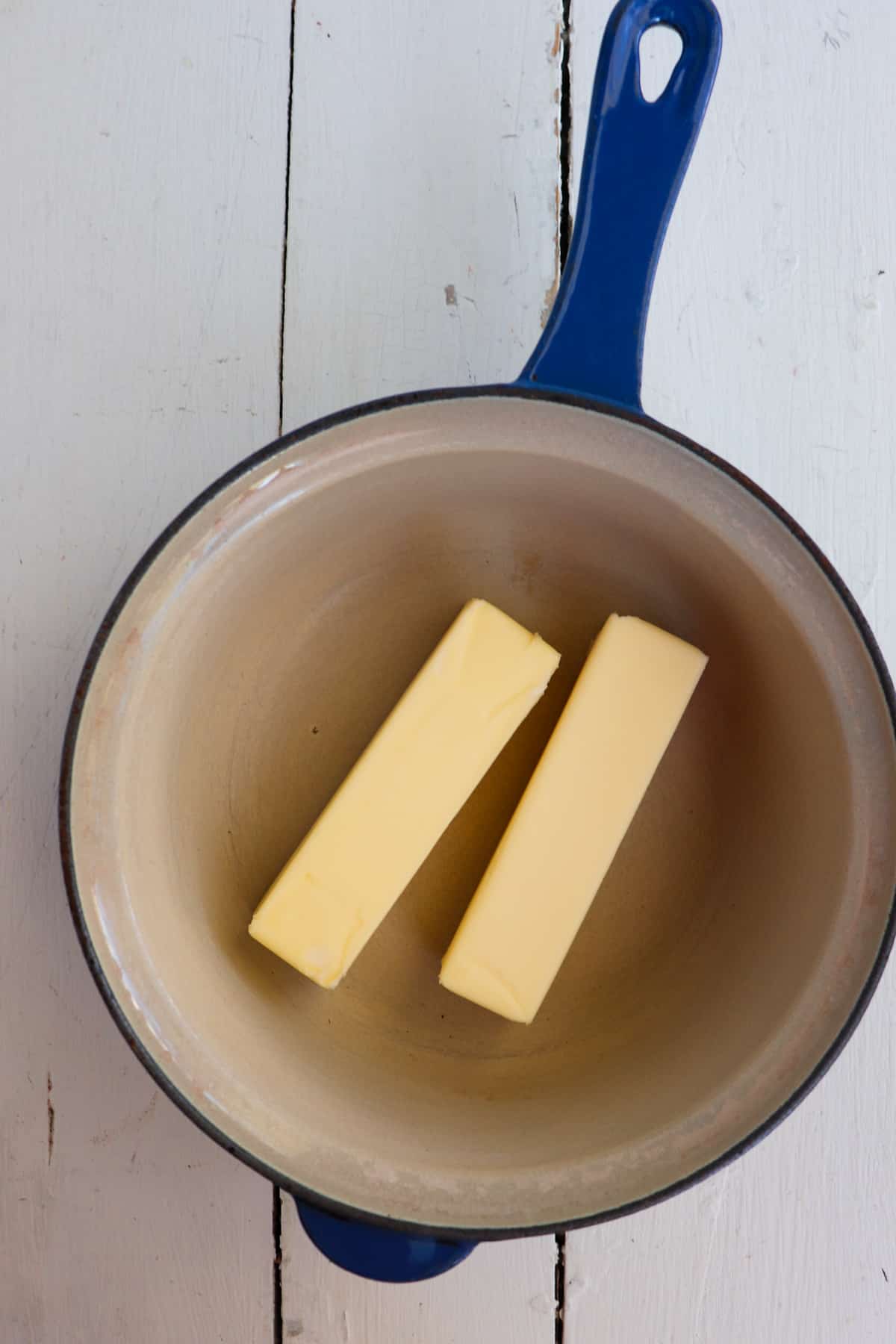 two sticks of butter in blue pot.