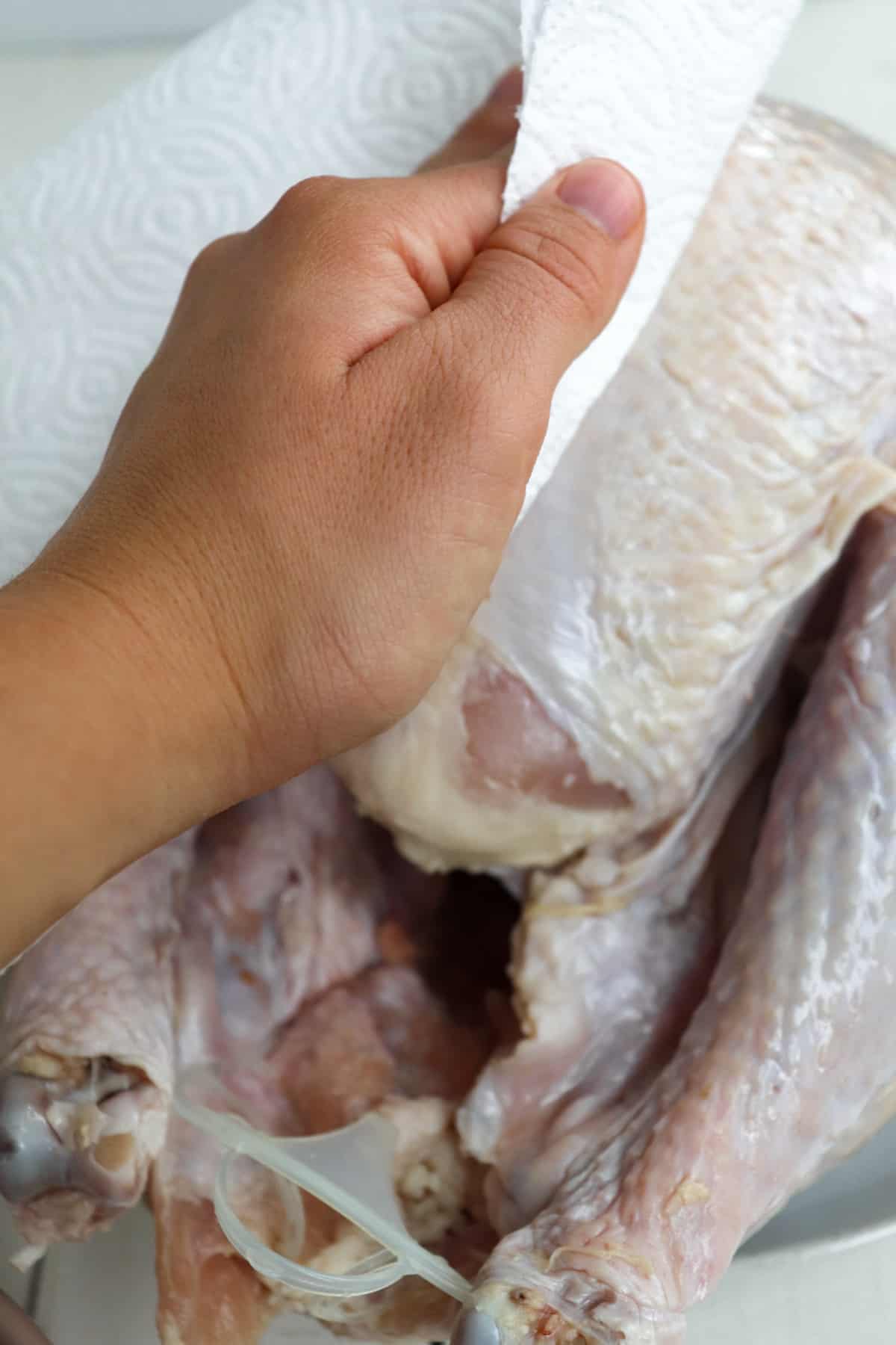 hand patting turkey dry with a paper towel.