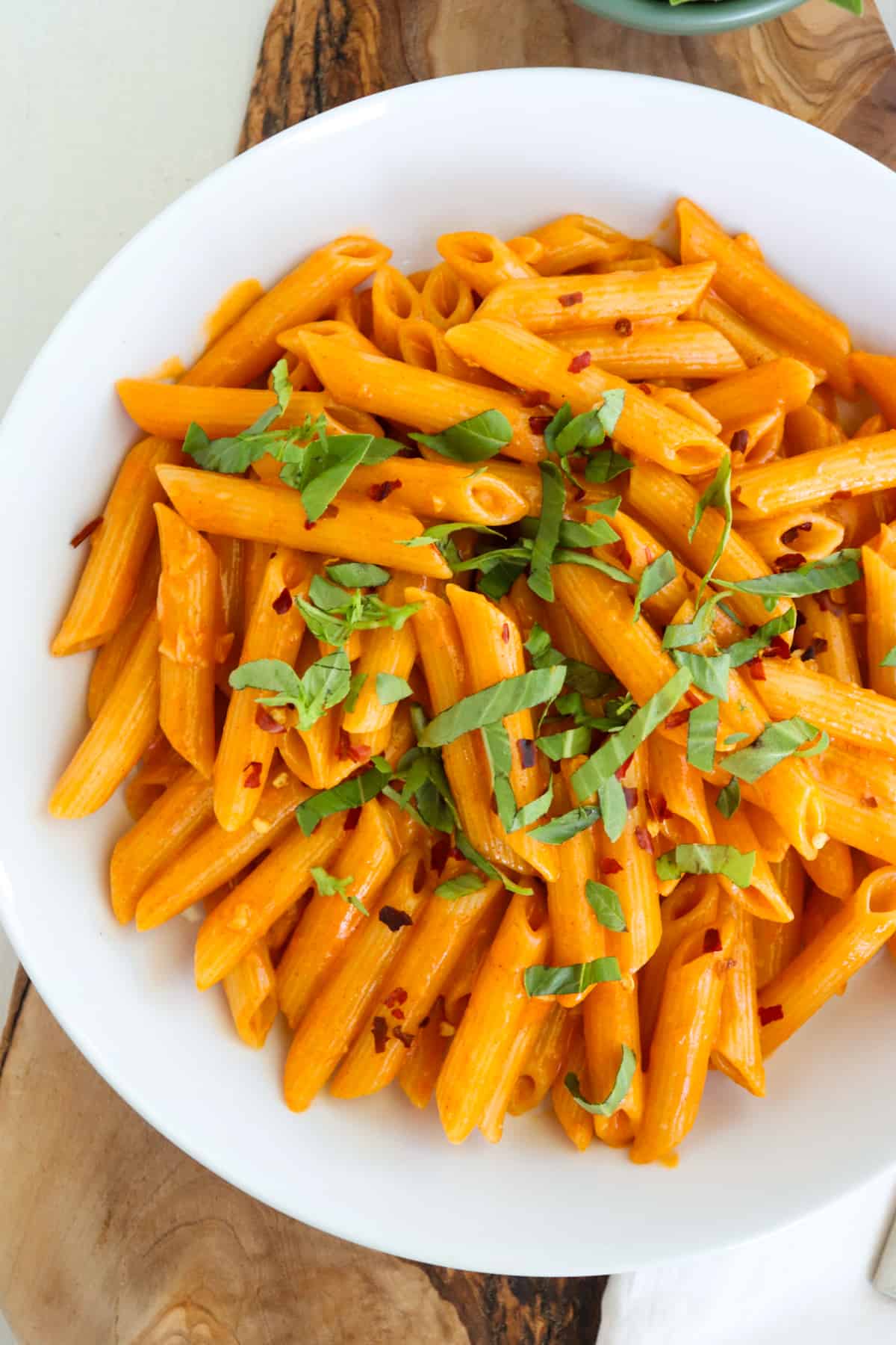 creamy gochujang pasta topped with fresh basil in a white plate.
