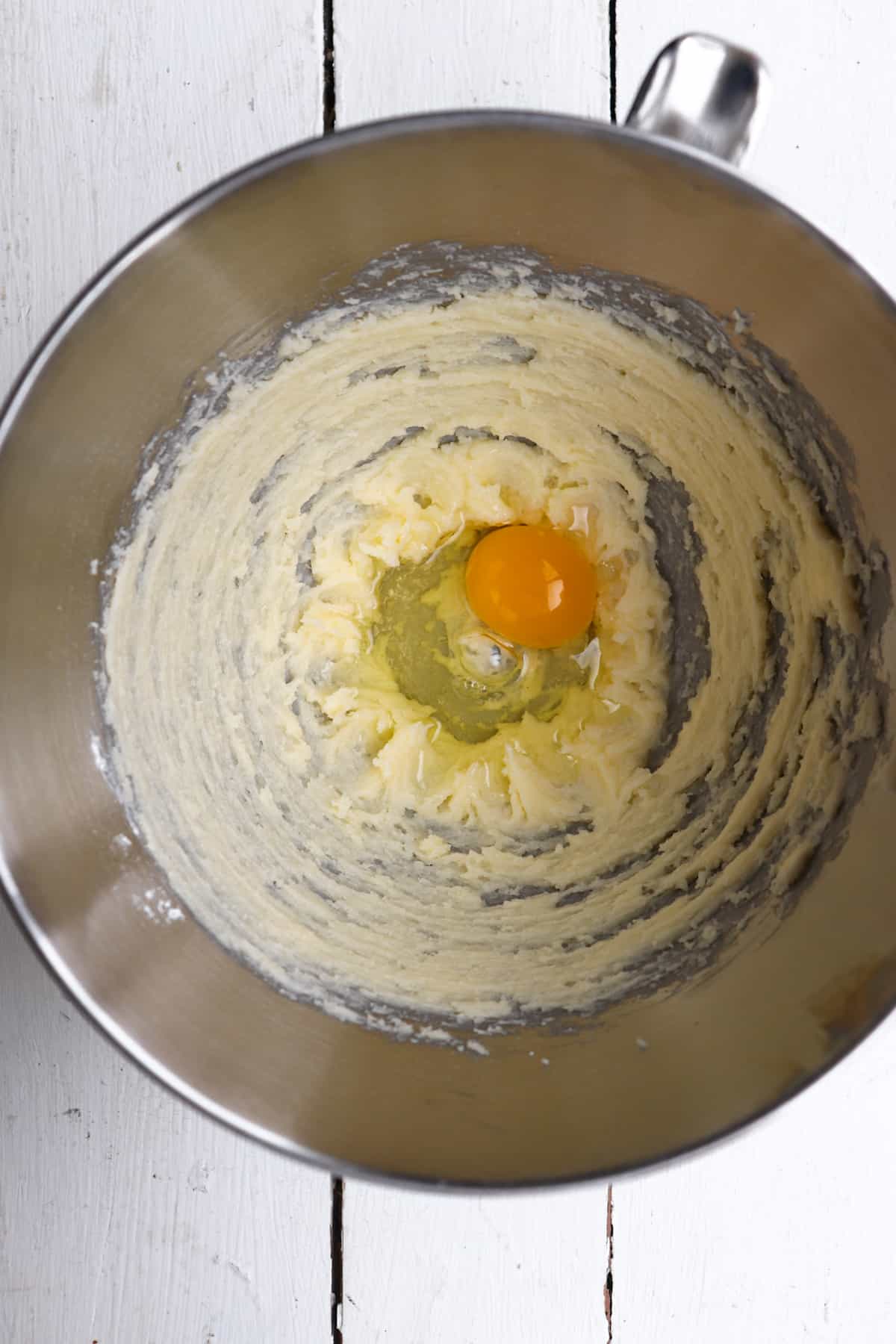 cracked egg in mixing bowl with butter and sugar.