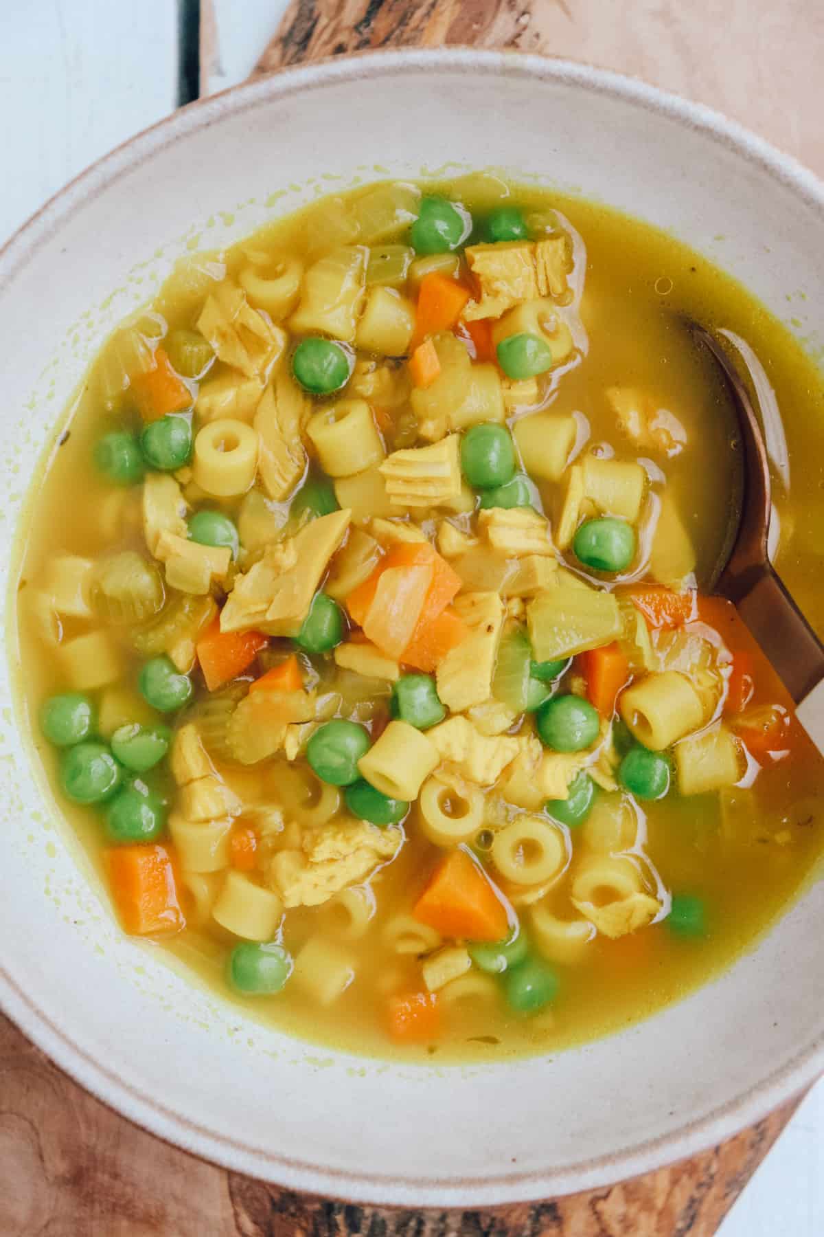 bowl of bone broth chicken soup with noodles and peas. 