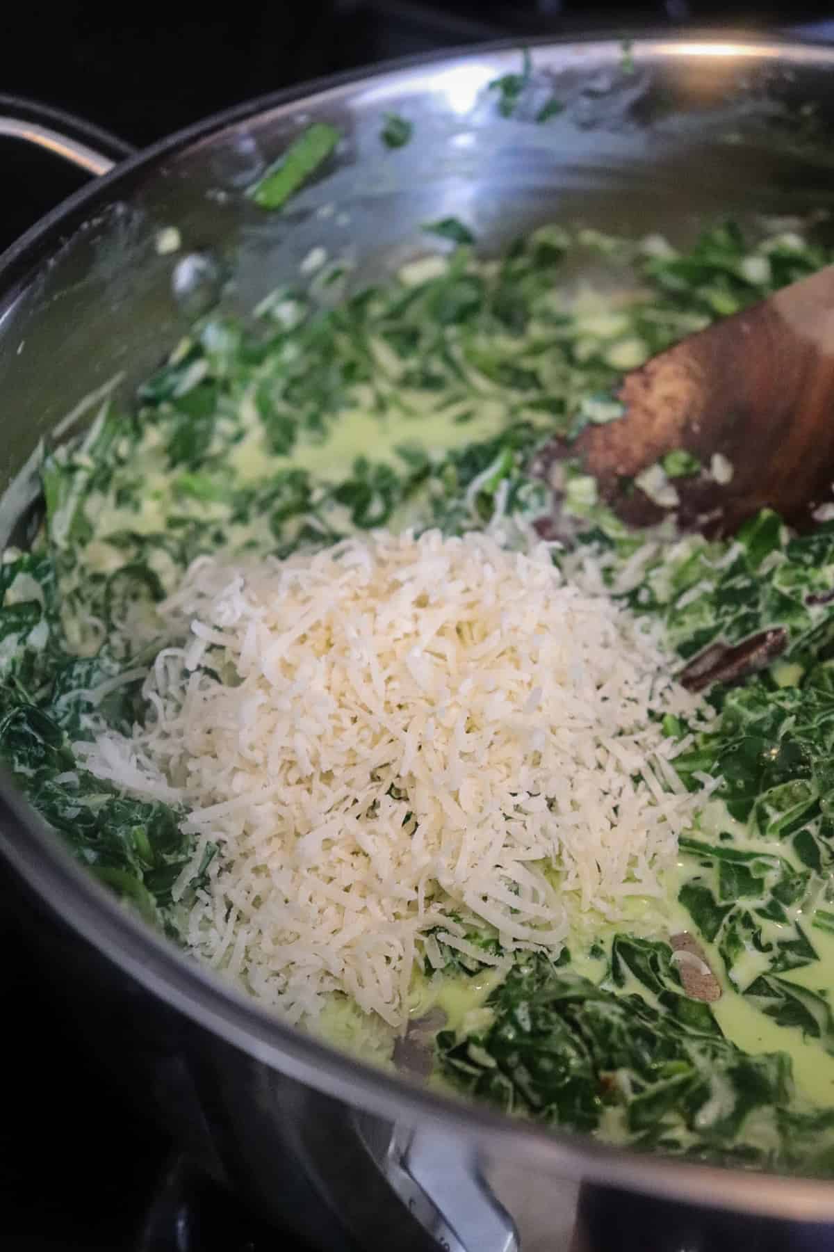 grated parmesan cheese added to creamed spinach in skillet.