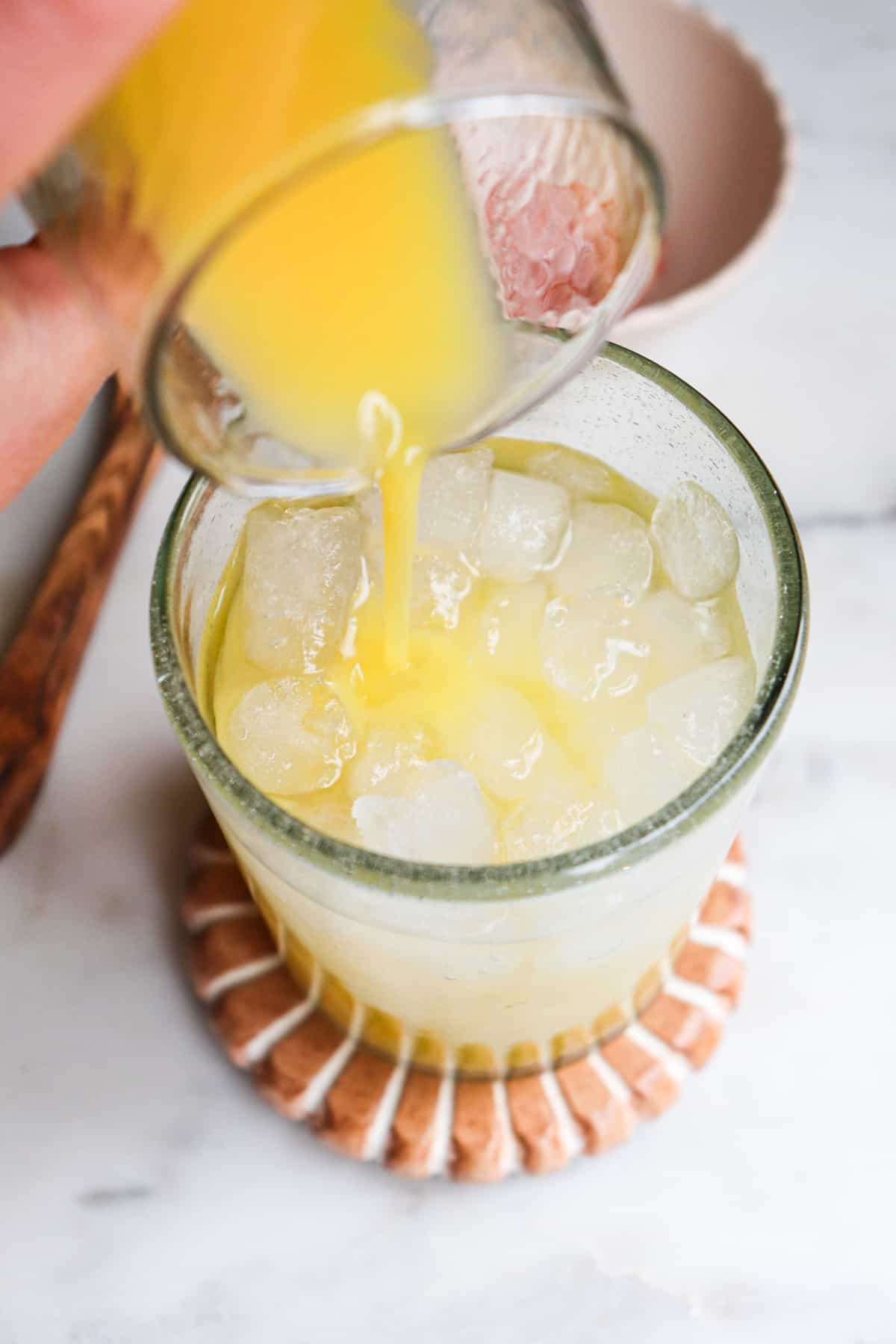 orange juice pouring into glass of coconut water.