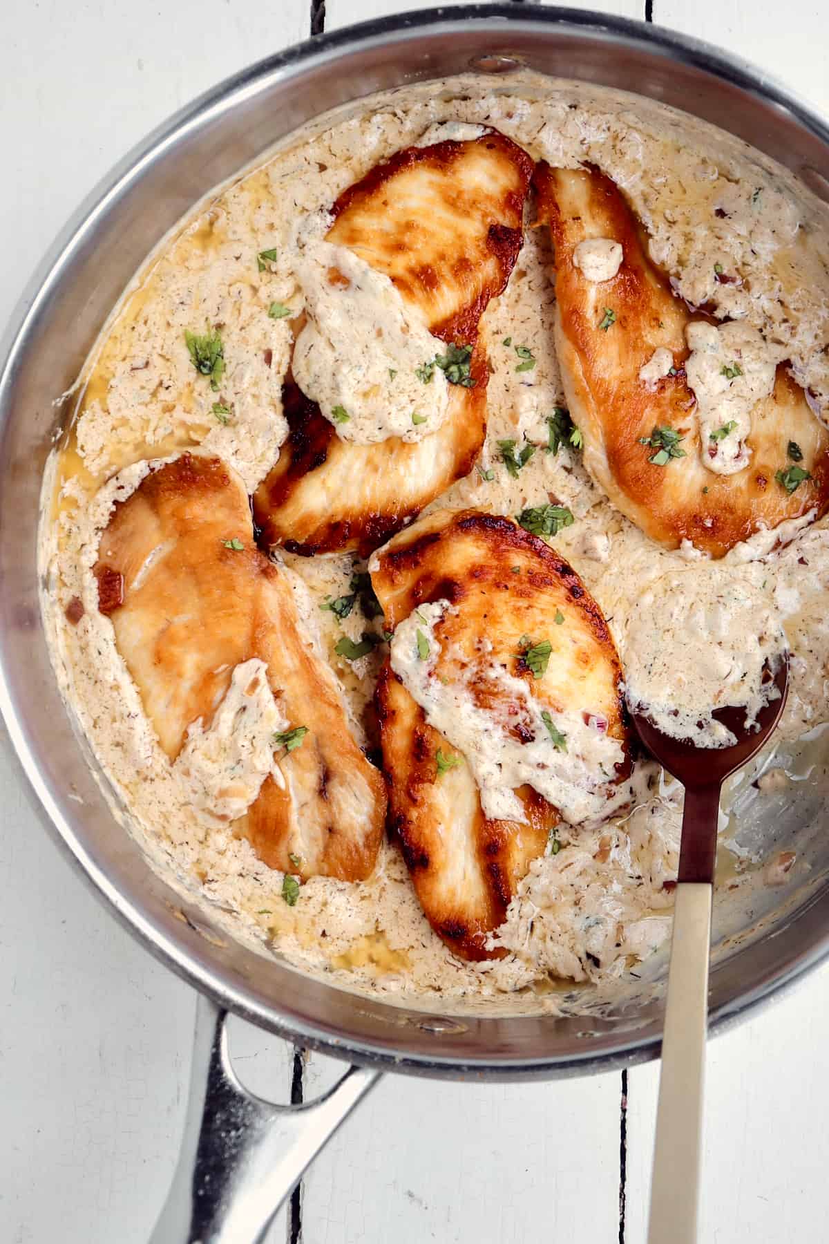 four chicken breasts with boursin sauce in a skillet.