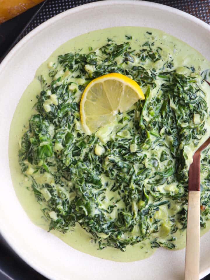 steakhouse style creamed spinach in a bowl with a lemon garnish.