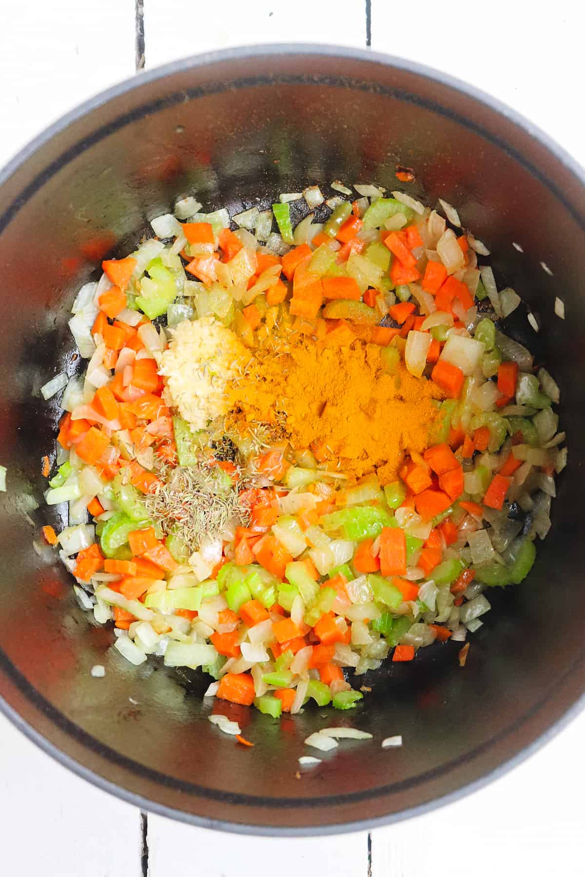 turmeric and mirepoix in soup pot.