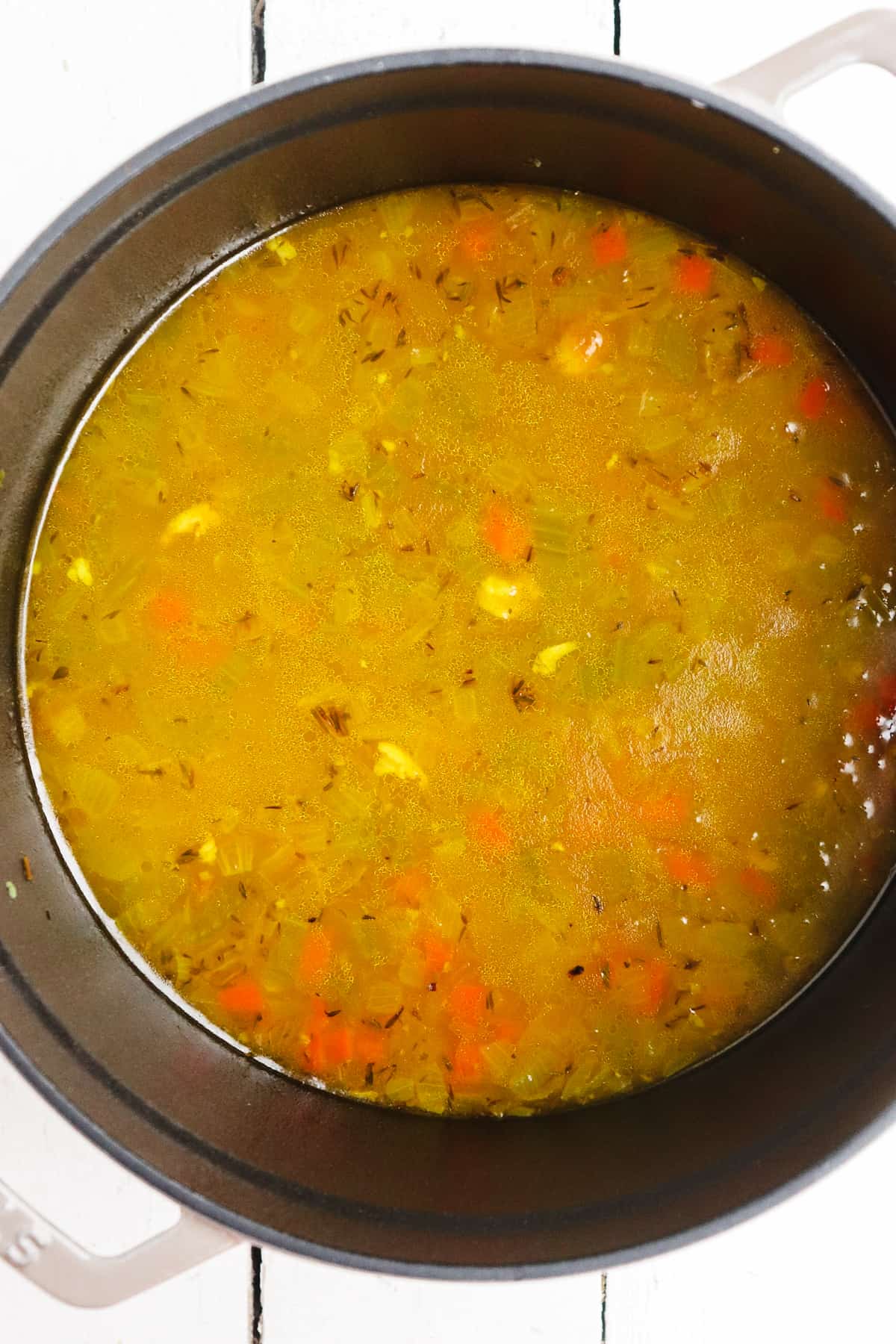 chicken broth added to turmeric and mirepoix in soup pot.