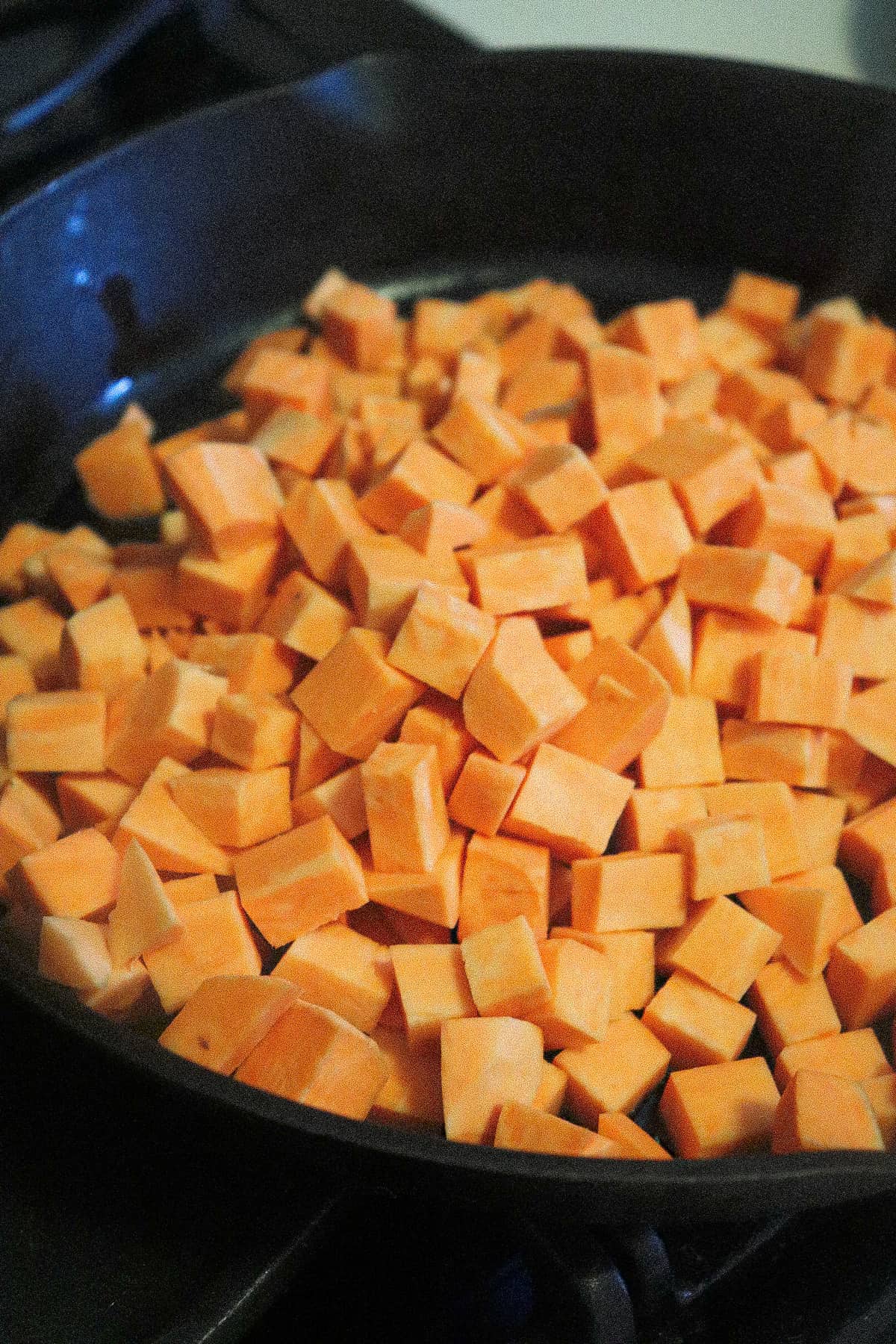 raw sweet potatoes added to skillet.