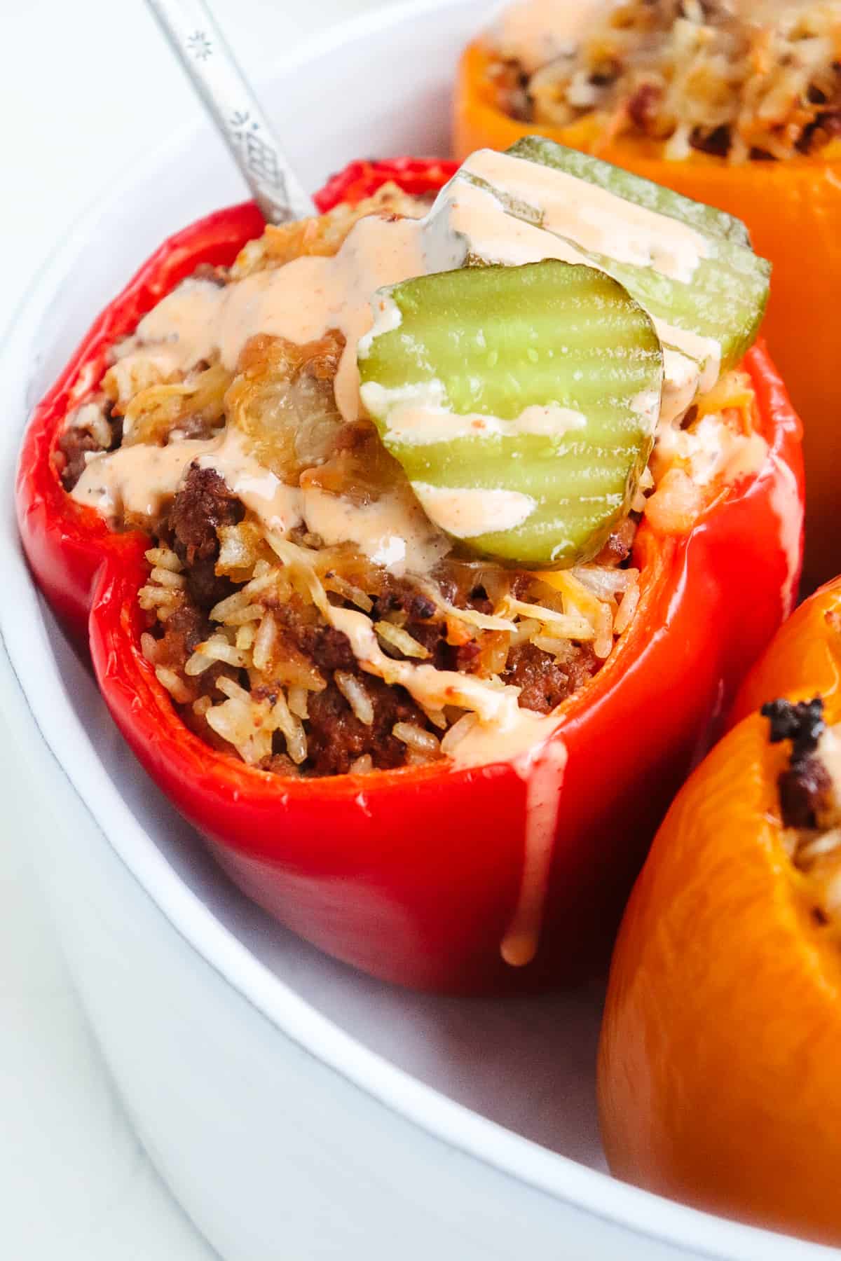 finished cheeseburger stuffed peppers with a spoon stuck in one.