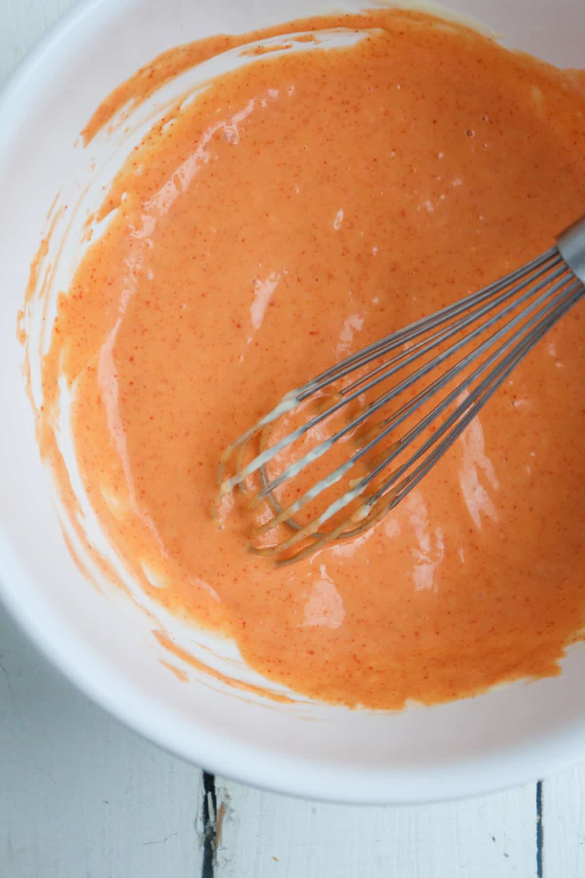 gochujang aioli with whisk in a white mixing bowl.
