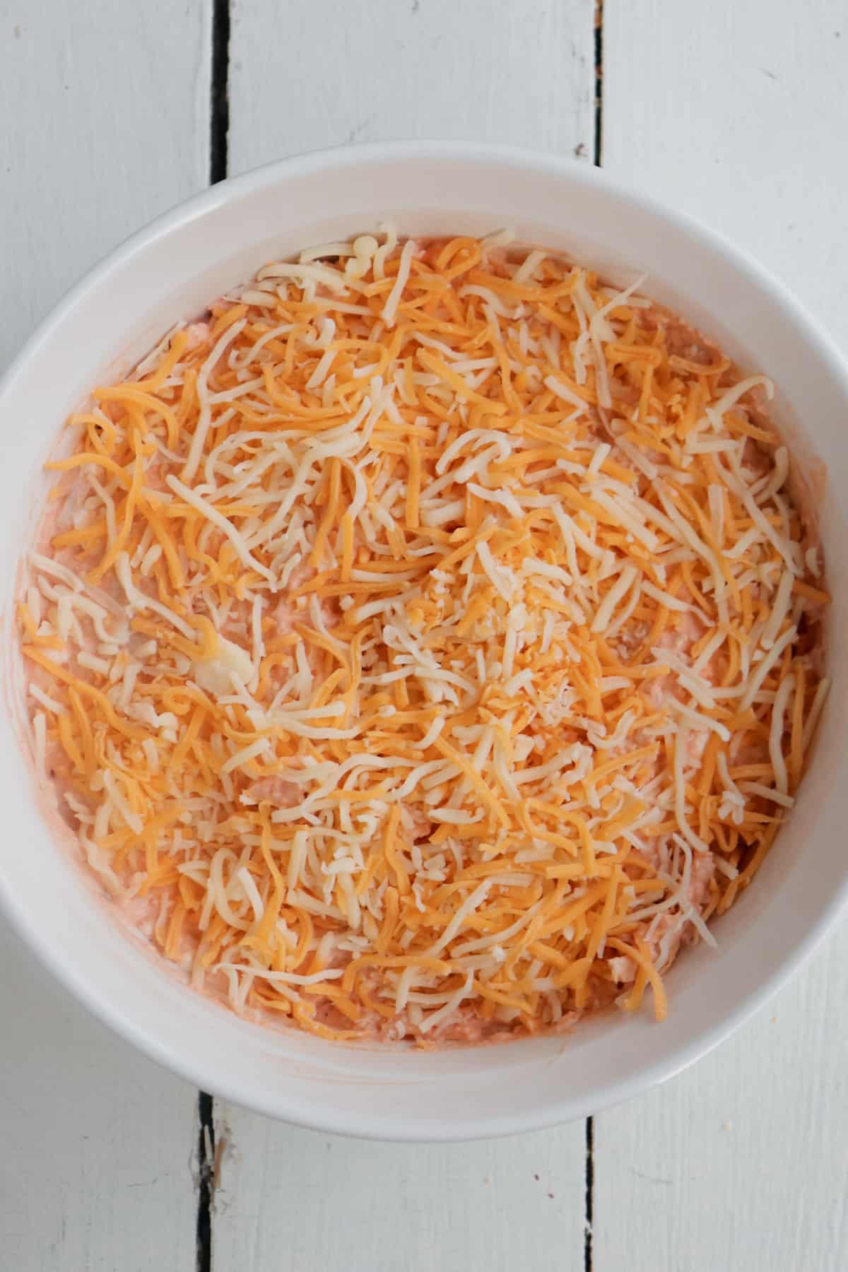 cheese on top of dip before it has been baked in the oven.