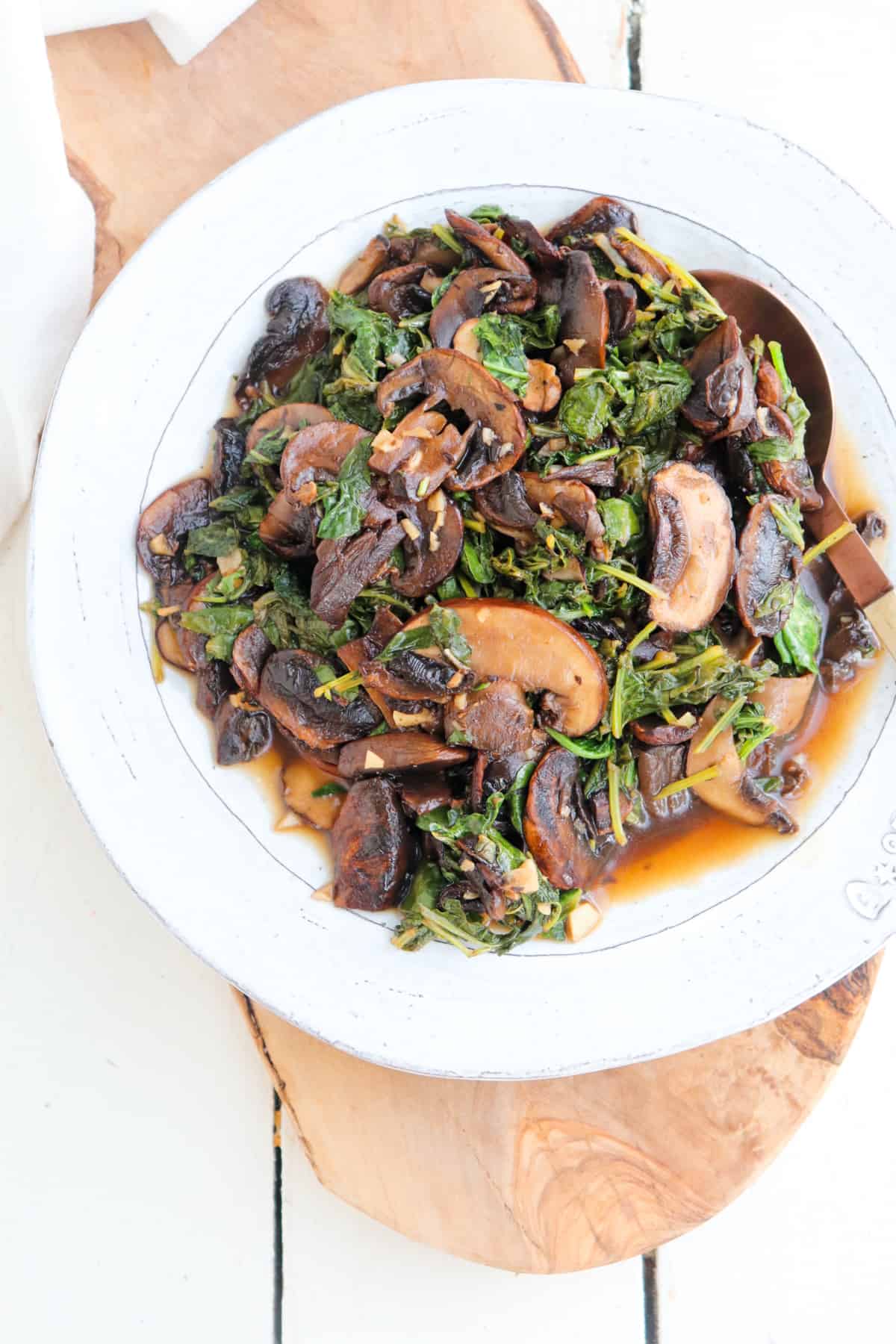 finished kale and mushroom dish on a white plate.