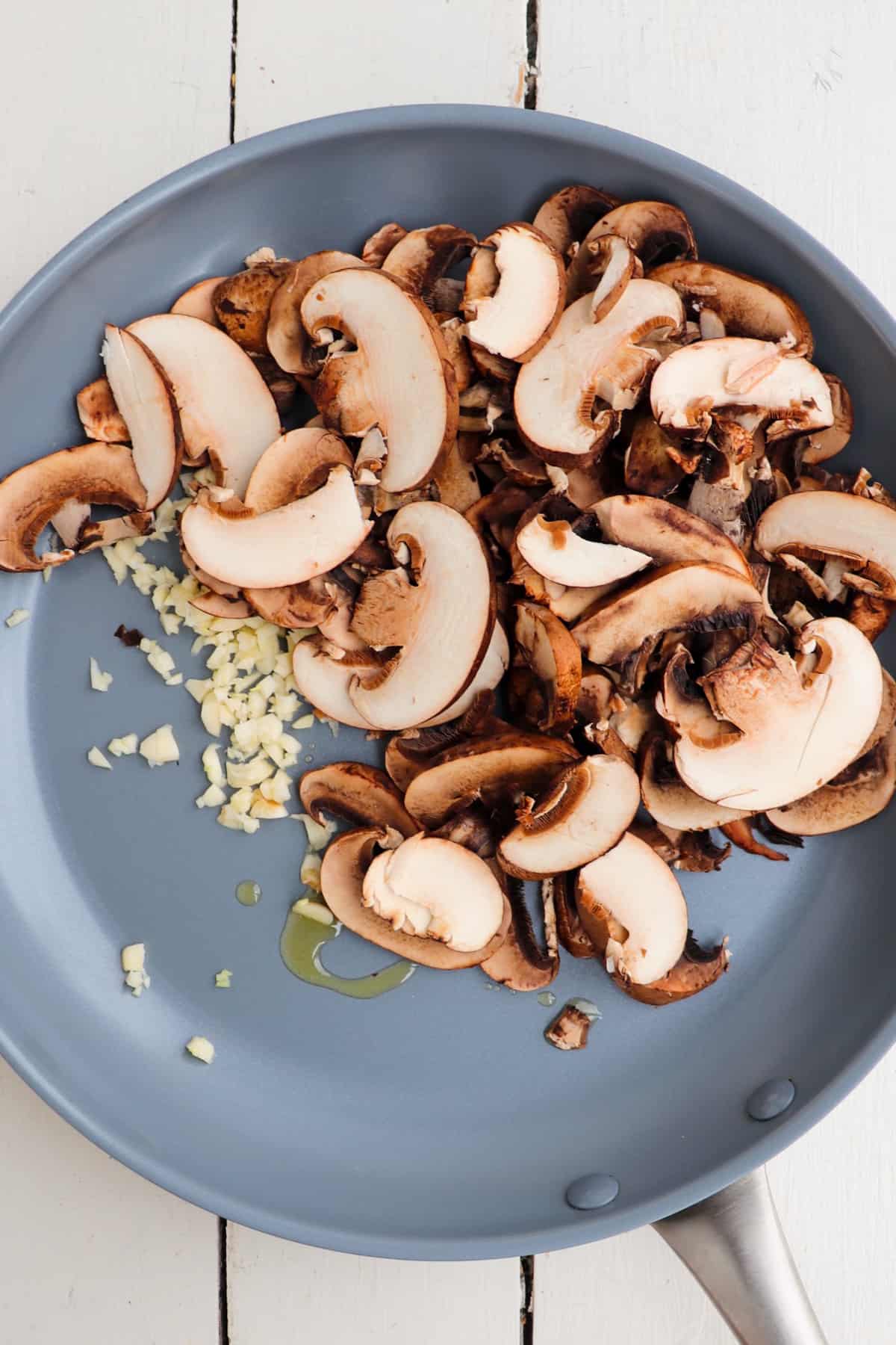 sliced mushrooms and garlic in pan.
