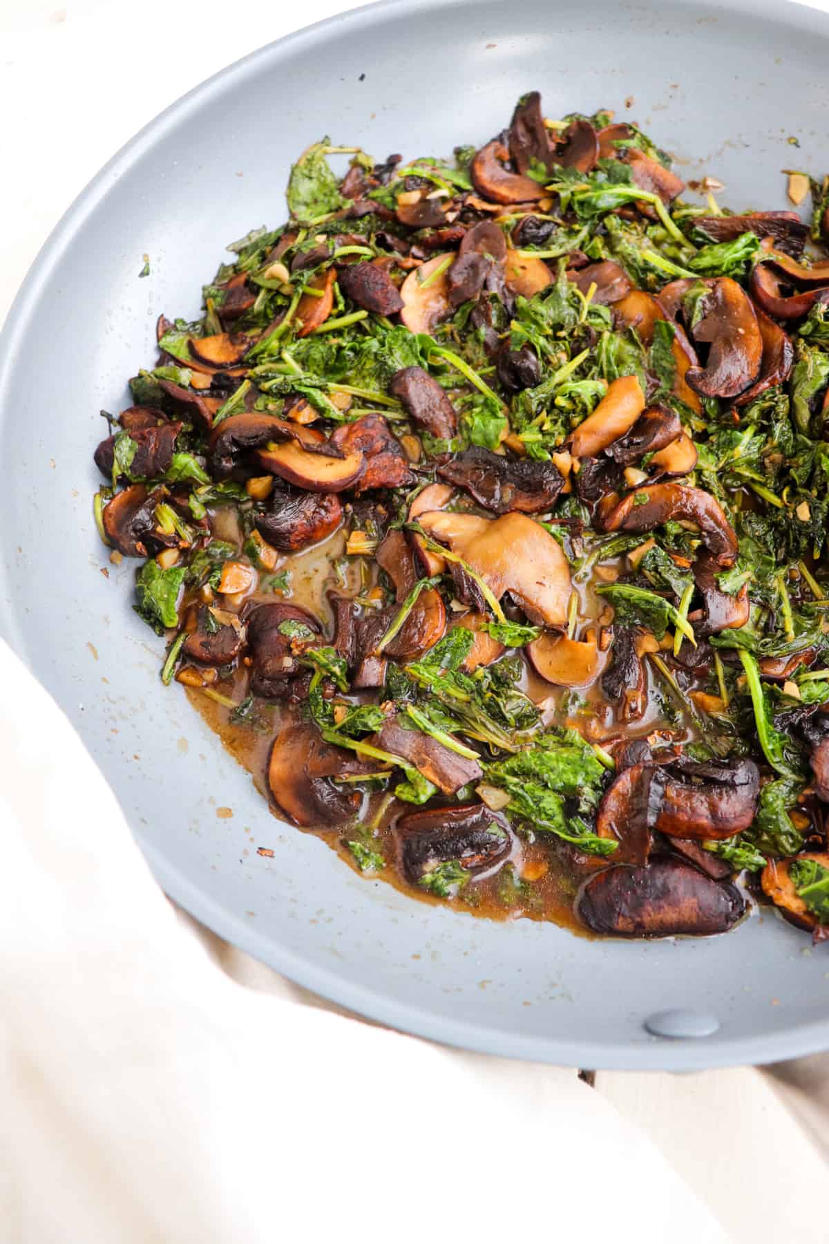 finished sauteed mushrooms and kale with balsamic in a pan.