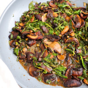 finished sauteed mushrooms and kale with balsamic in a pan.