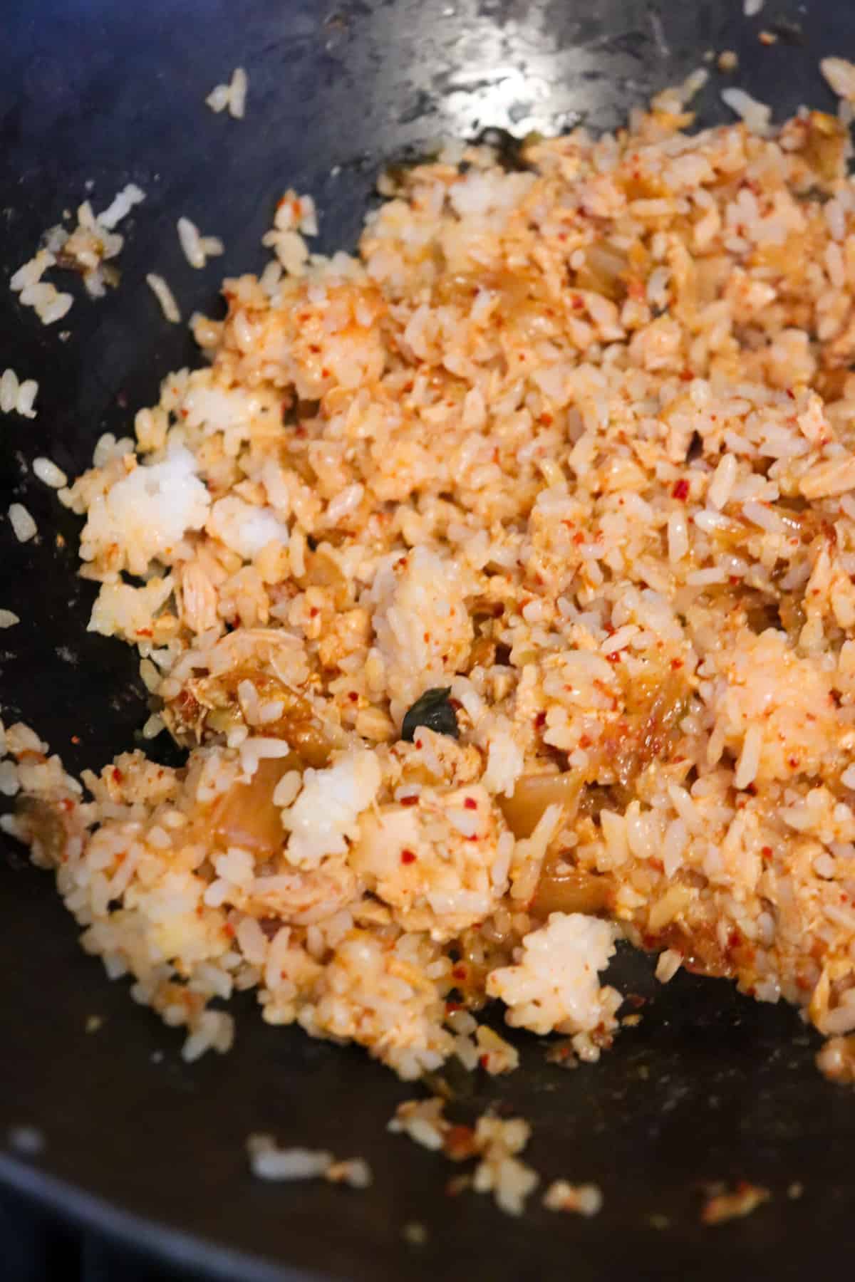 rice mixed in to seasonings in wok.