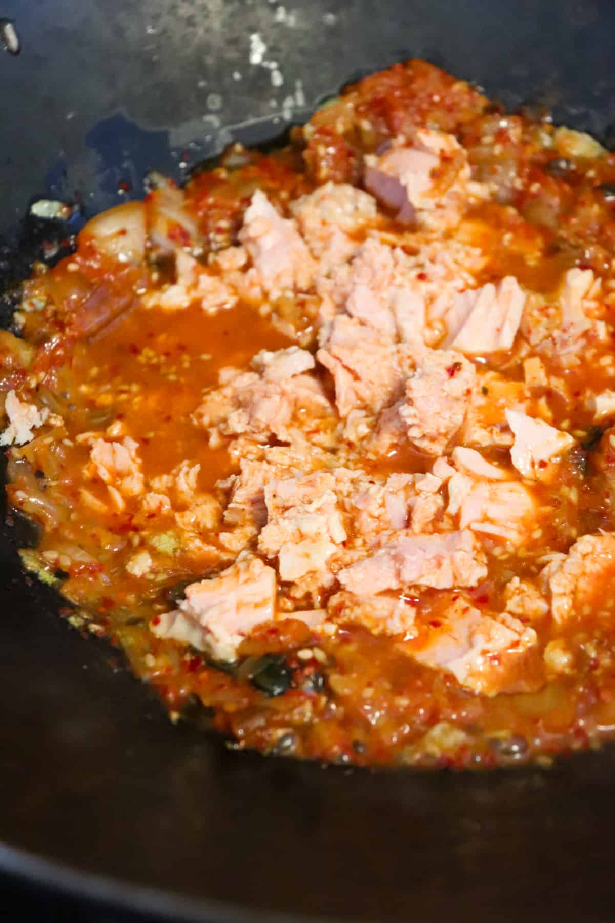 tuna added to fried kimchi in wok.