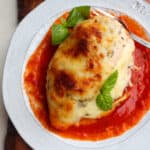 pizza stuffed chicken breast on a plate covered in red sauce.