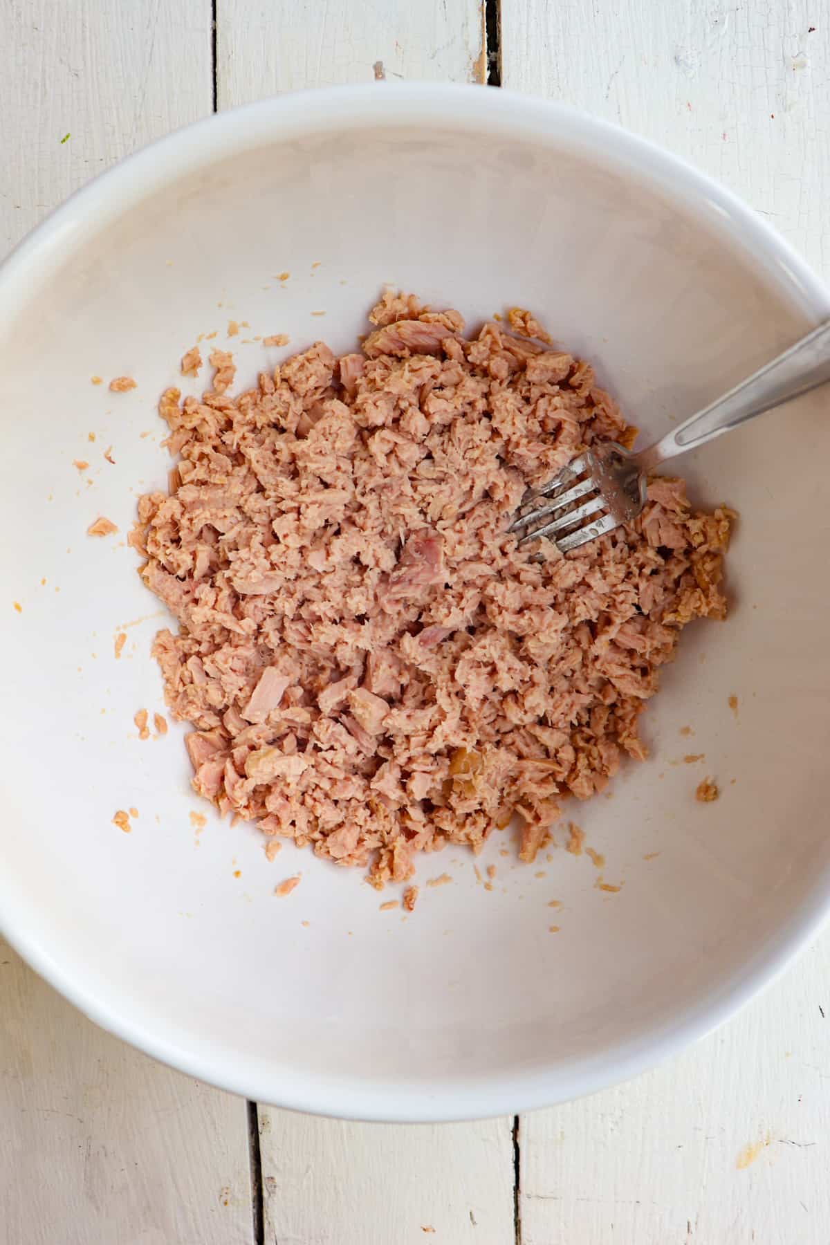 tuna in a bowl being mashed with a fork.