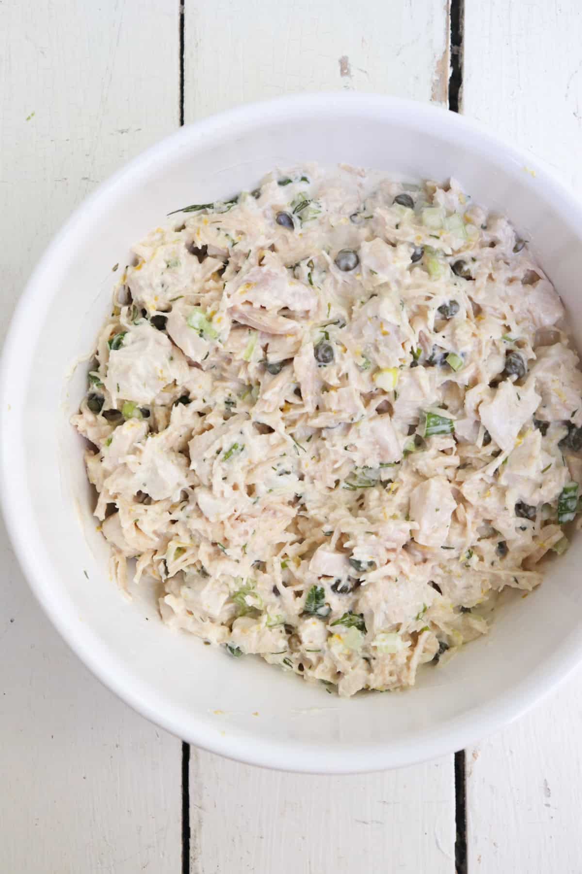 caper chicken salad mixed in a white bowl.