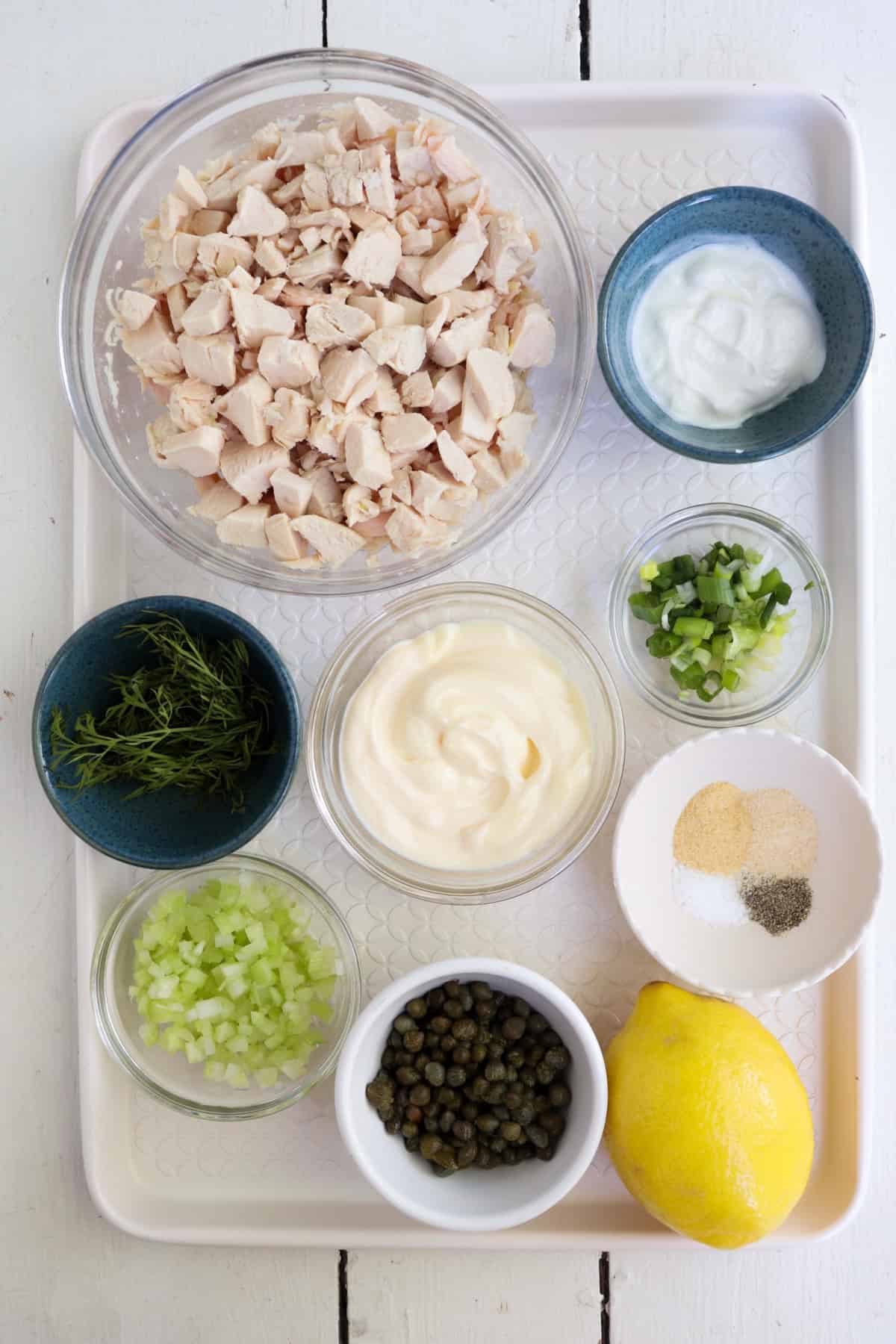 ingredients for caper chicken salad on a white tray.