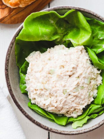 scoop of classic carol chicken salad in a bowl filled with lettuce.